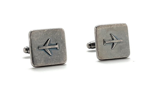 Pair of silver square cufflinks with airplane design on a white background