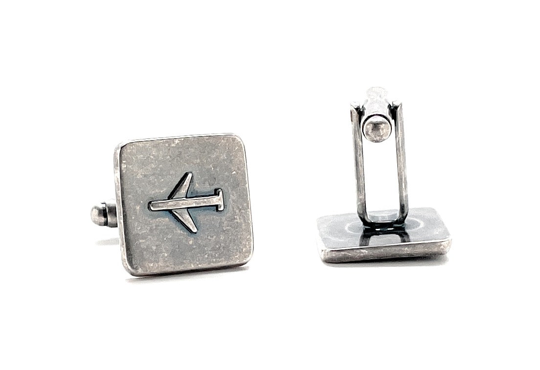 Silver cufflinks with a directional arrow design on a white background