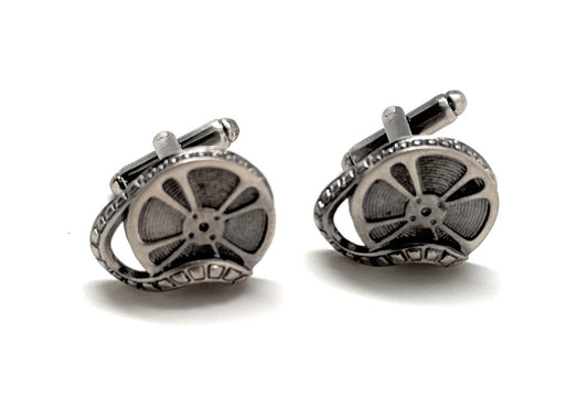 Pair of silver cufflinks with film reel design on a white background