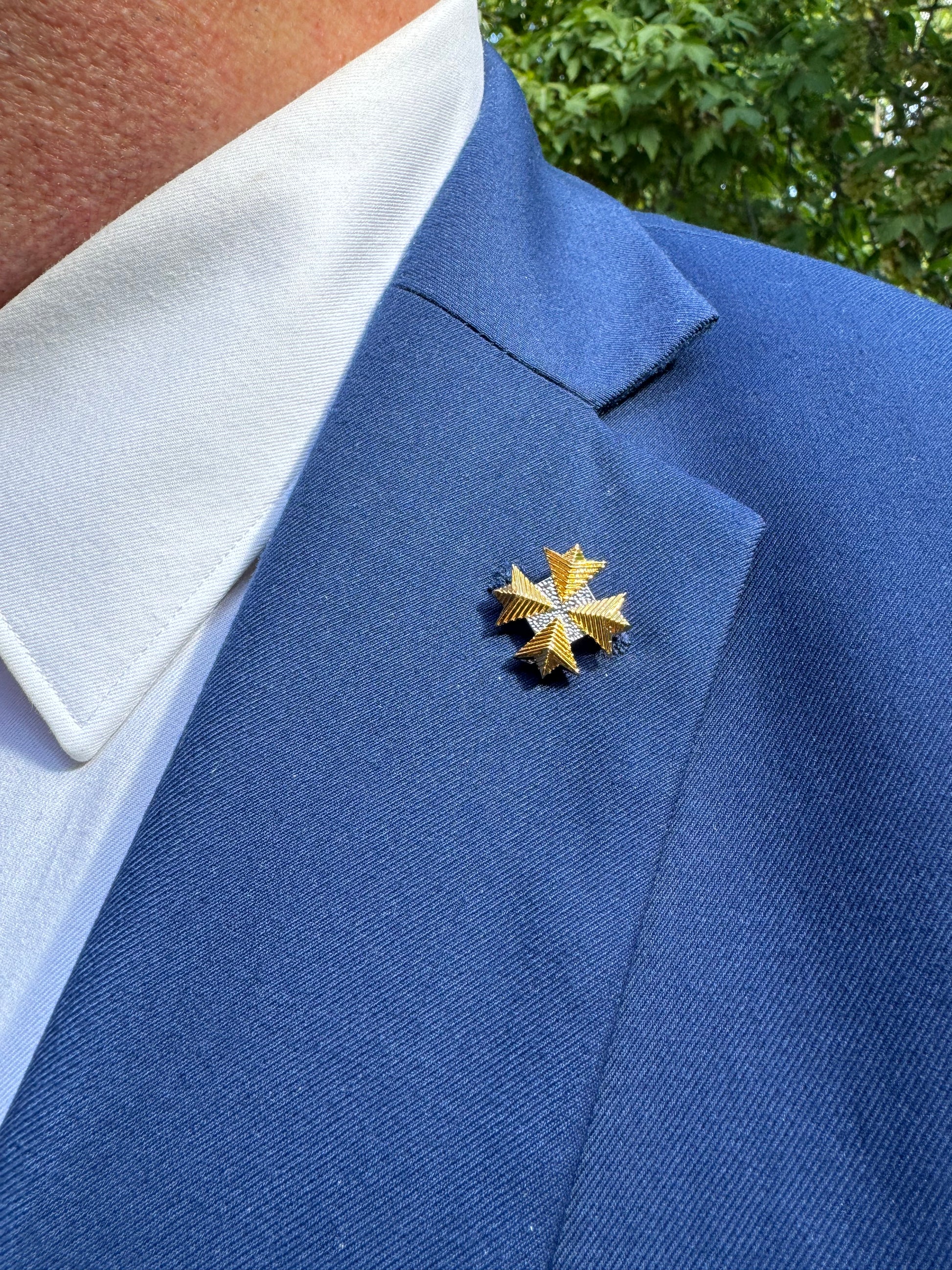 Gold star pin on a blue jacket with a blurred green background