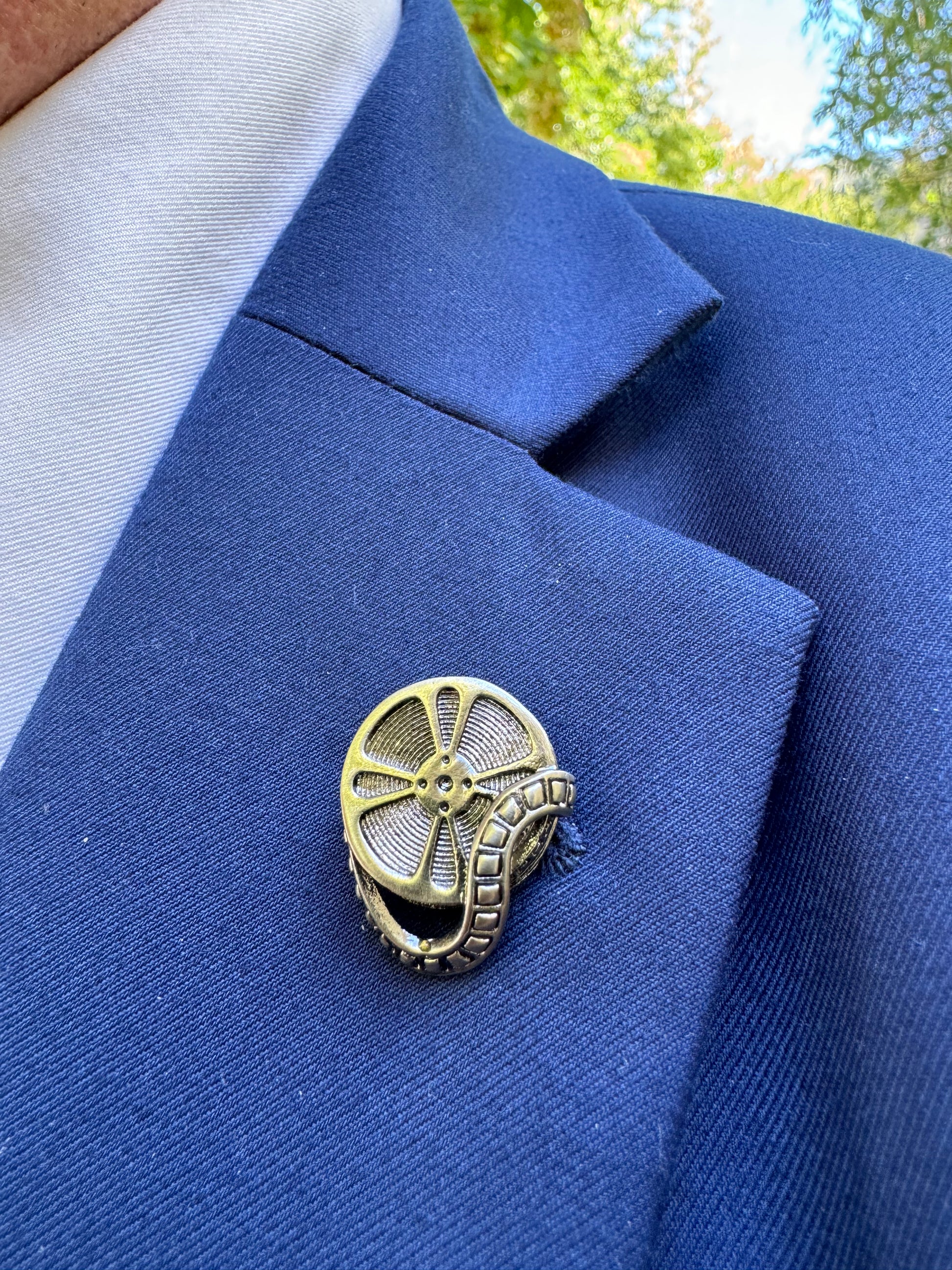 Gold circular lapel pin on a blue fabric background