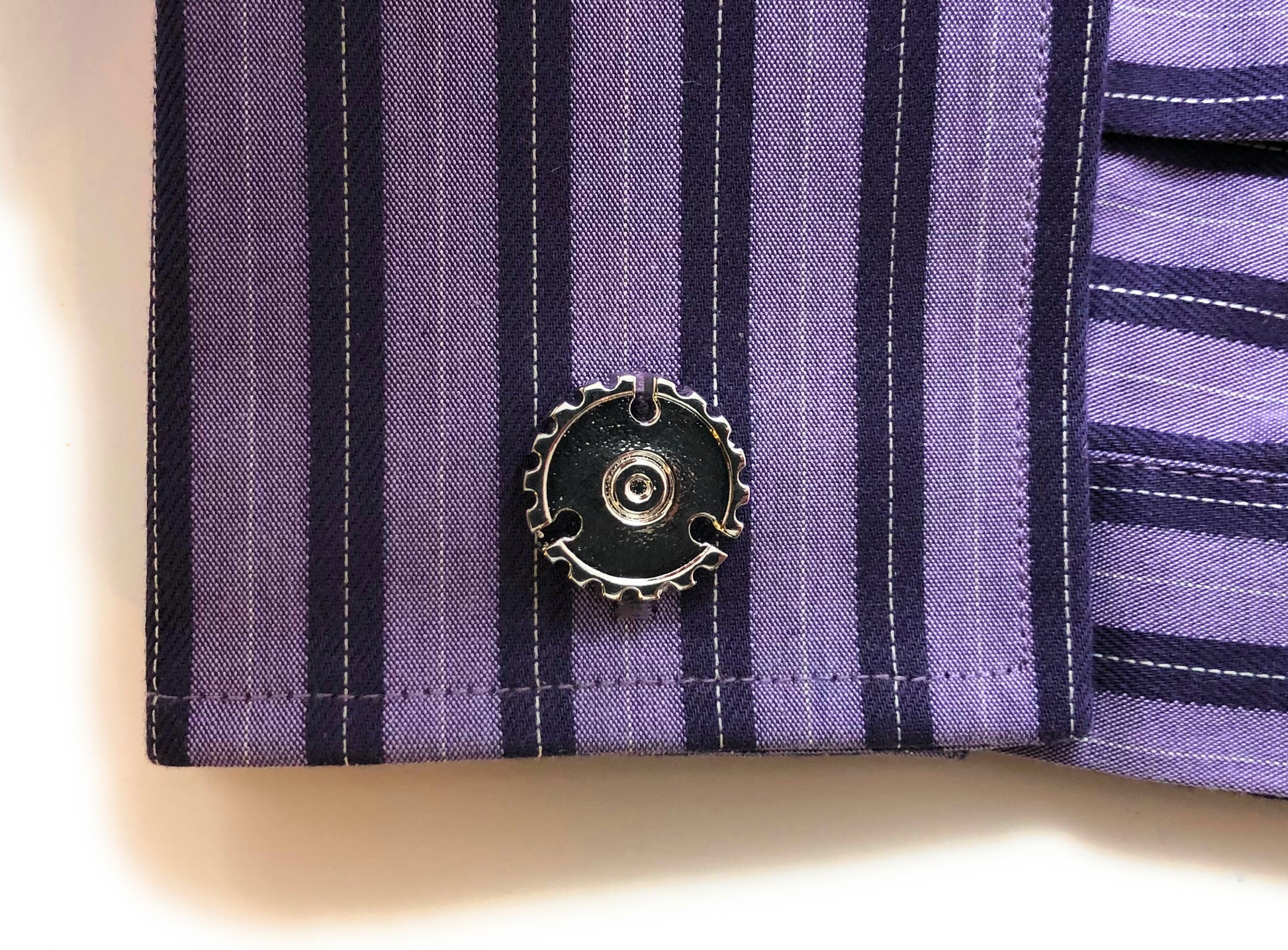 Close-up of a purple striped shirt with a button on a beige background