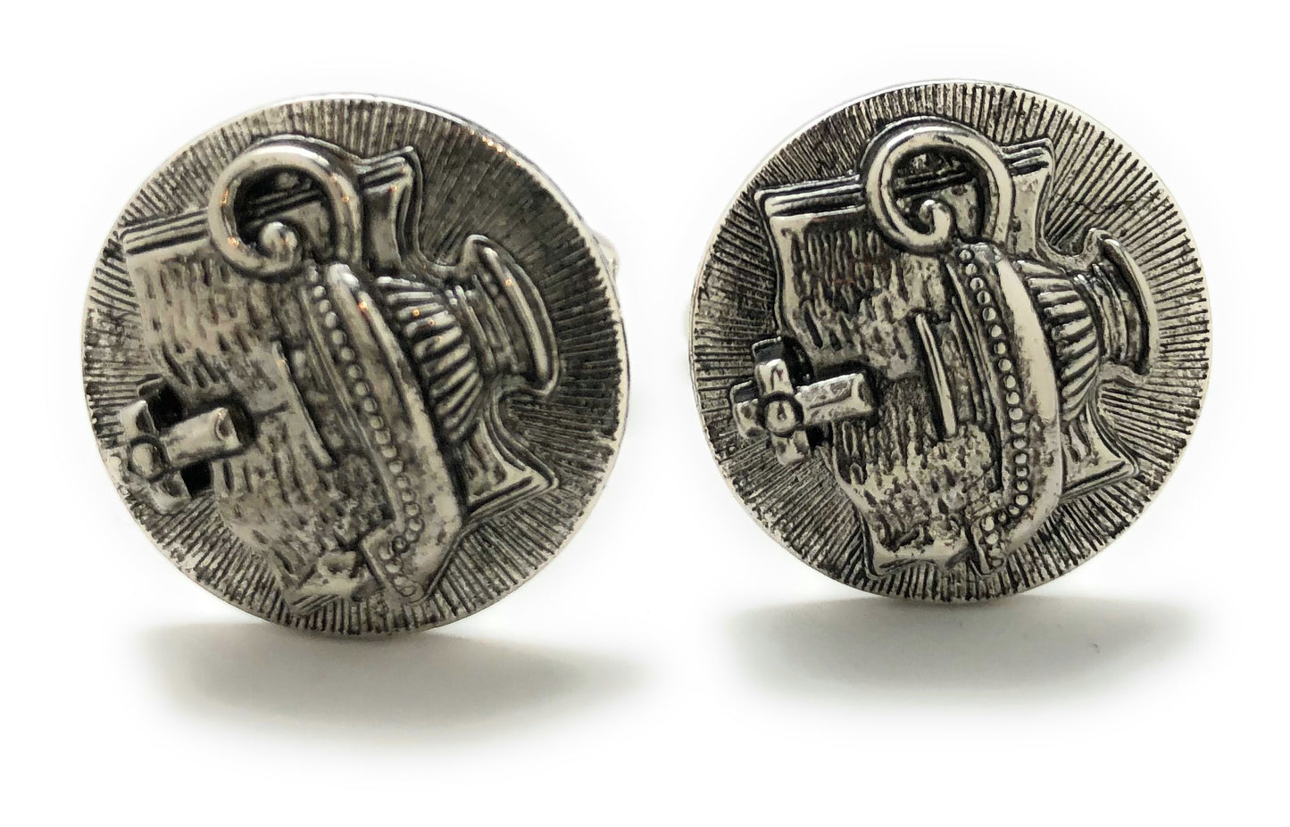 Pair of silver cufflinks with intricate design on a white background