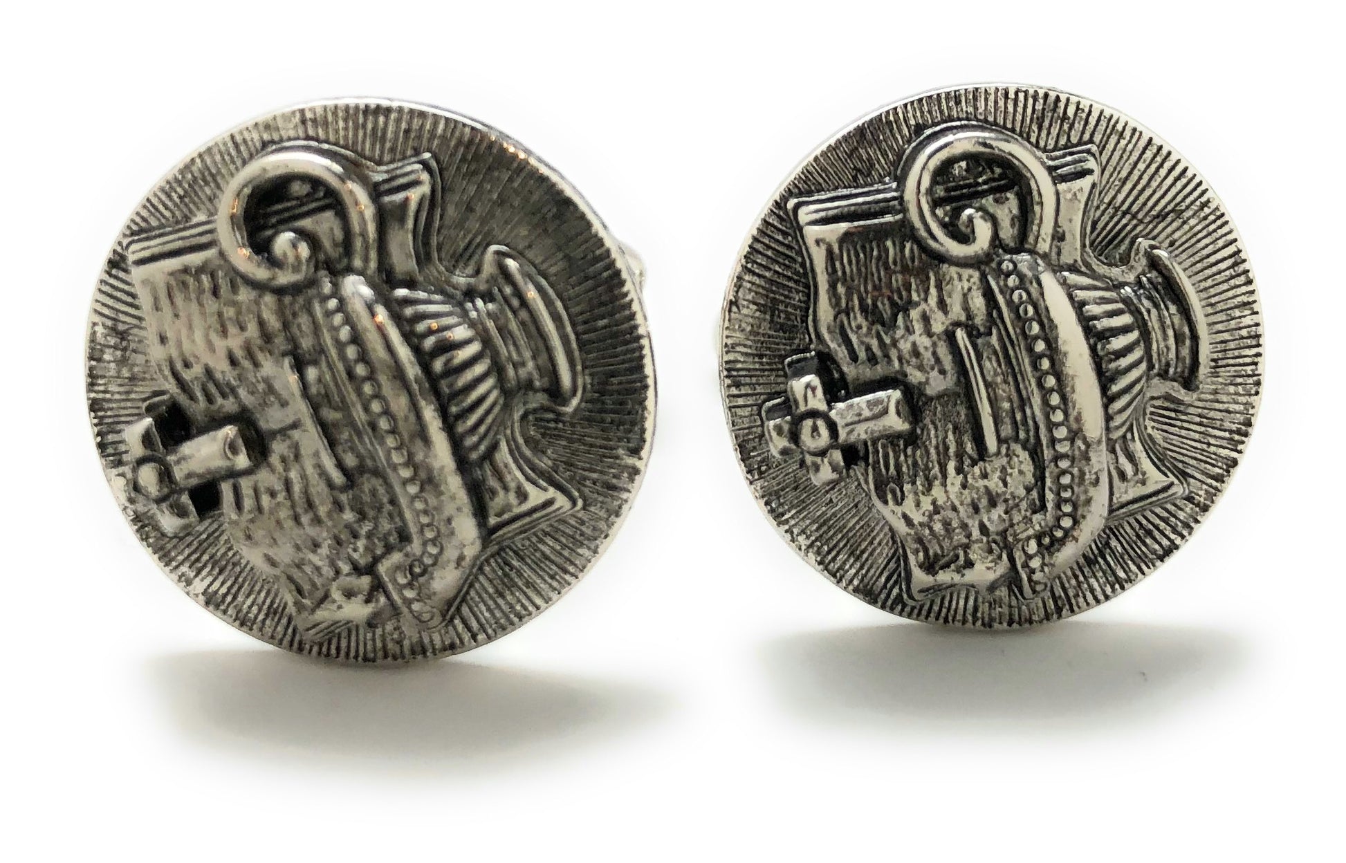 Pair of silver cufflinks with intricate design on a white background