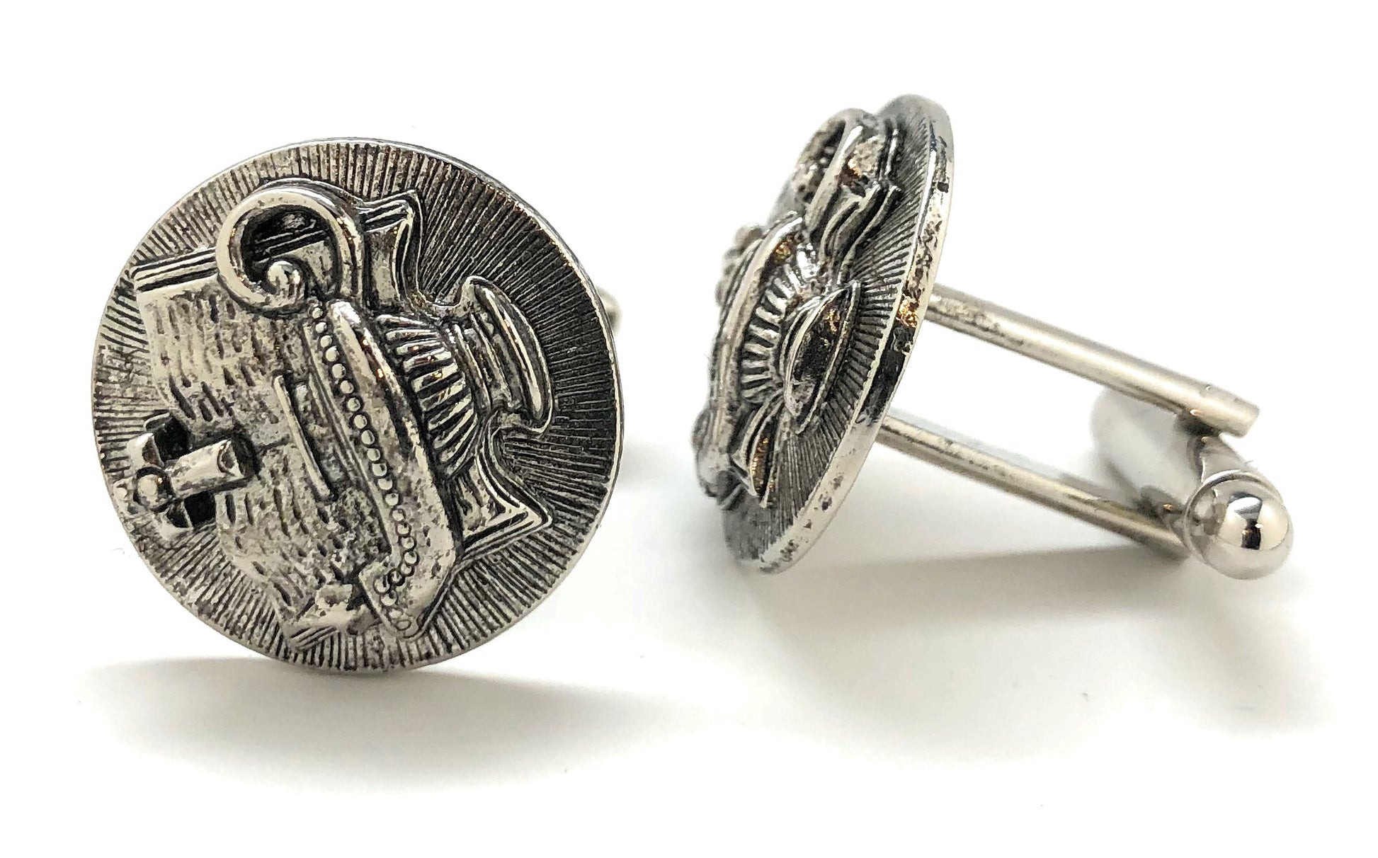 Pair of silver cufflinks with intricate design on a white background