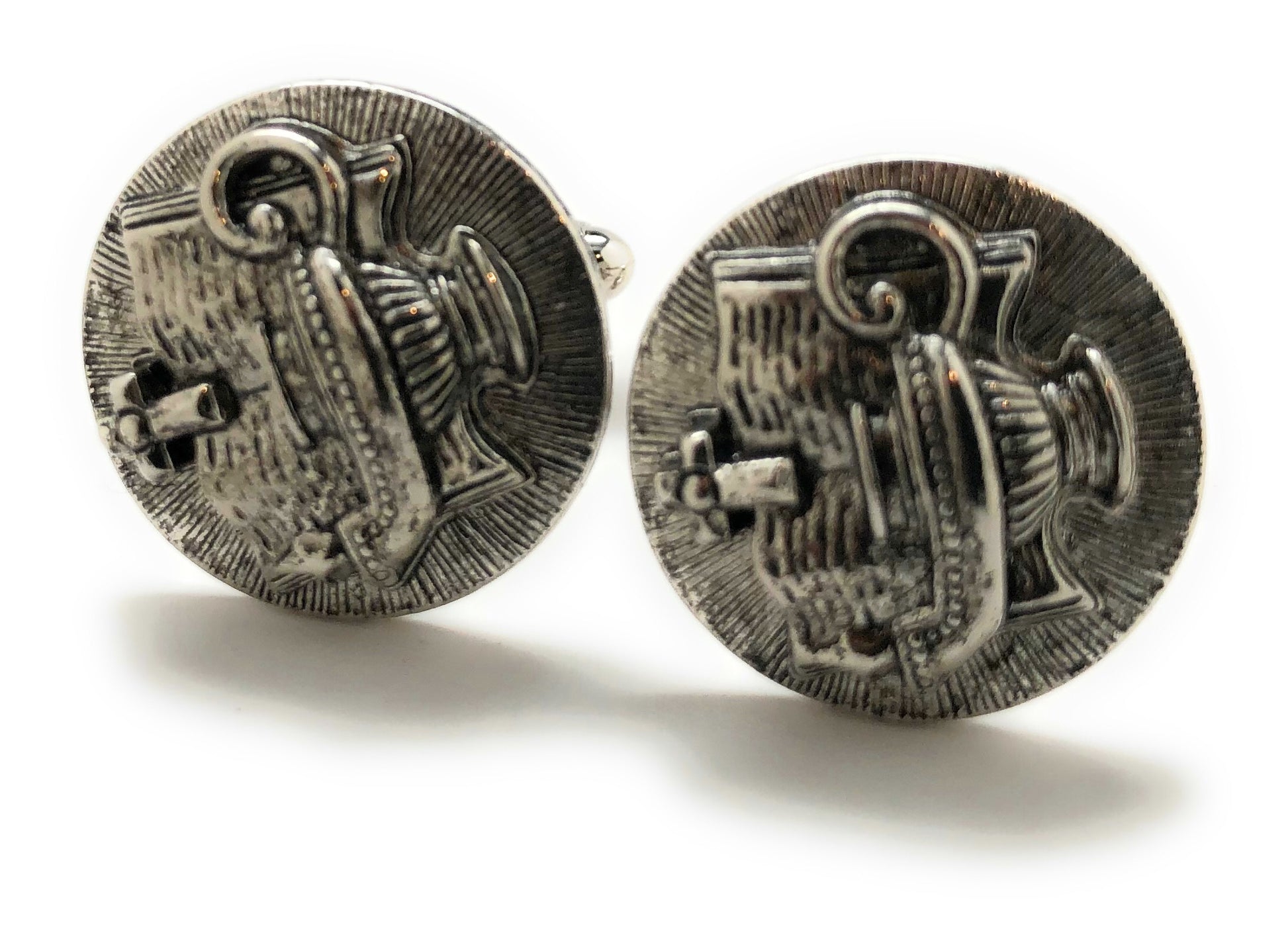 Pair of silver cufflinks with intricate design on a white background
