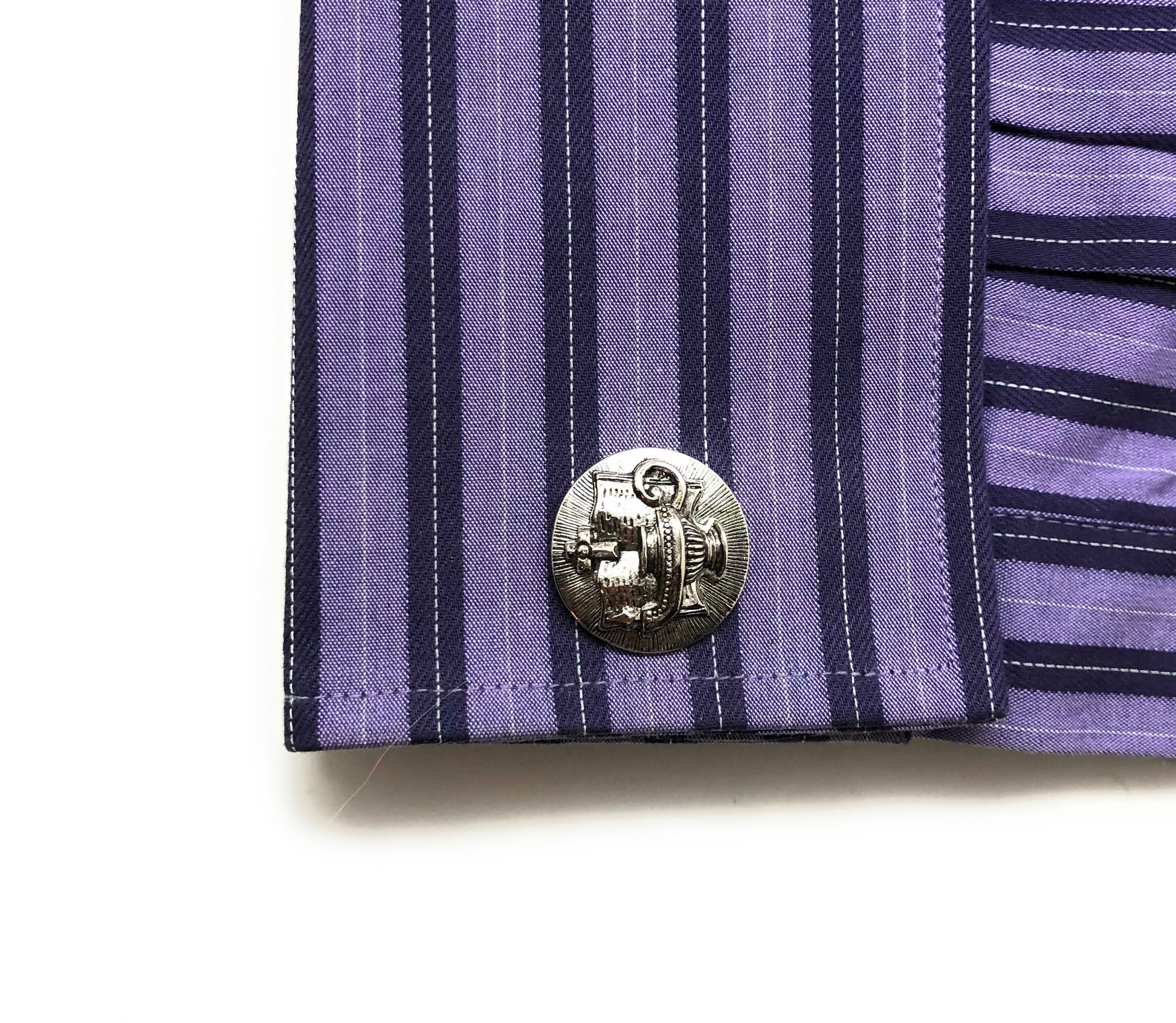 Close-up of a purple and navy striped shirt with a decorative button on a white background