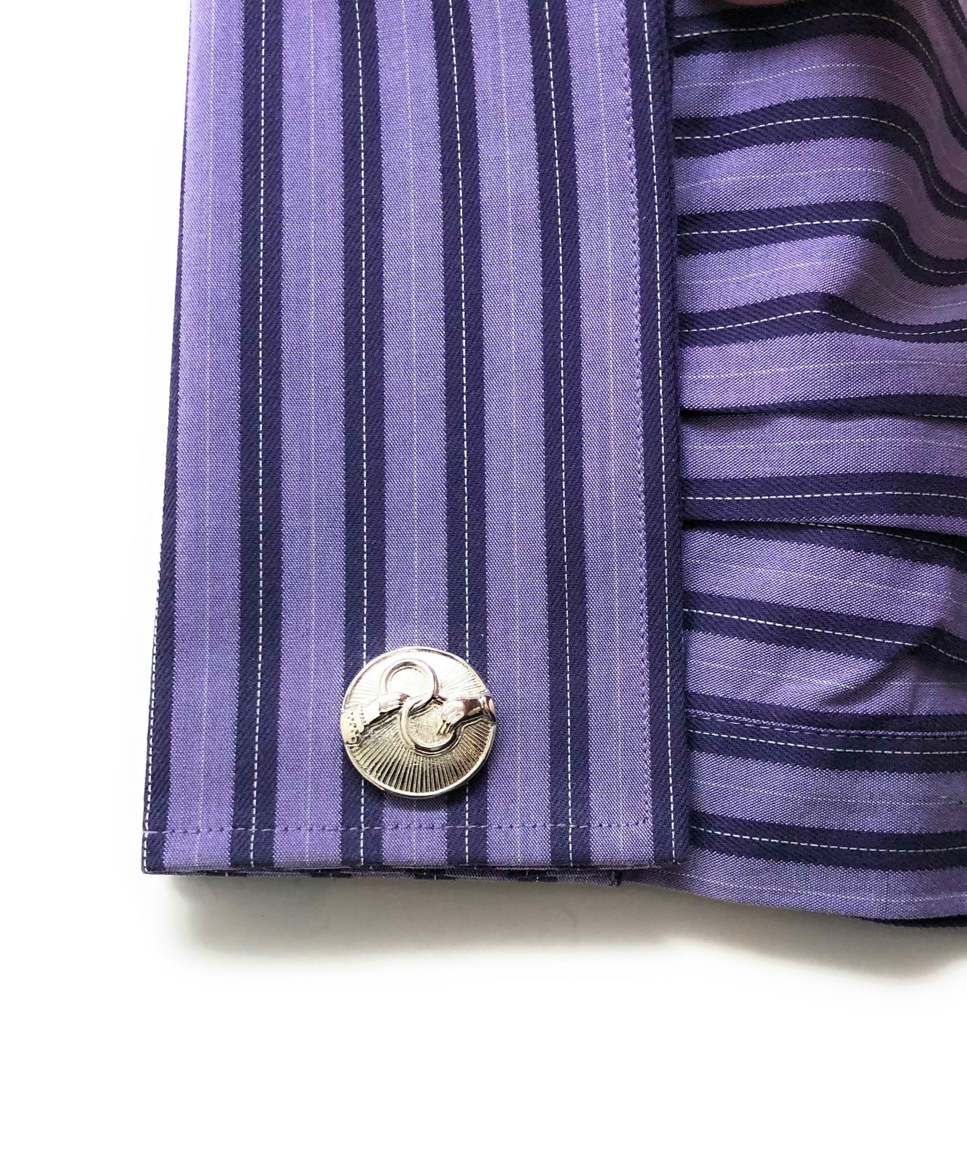 Close-up of a purple striped shirt with a cufflink on a white background