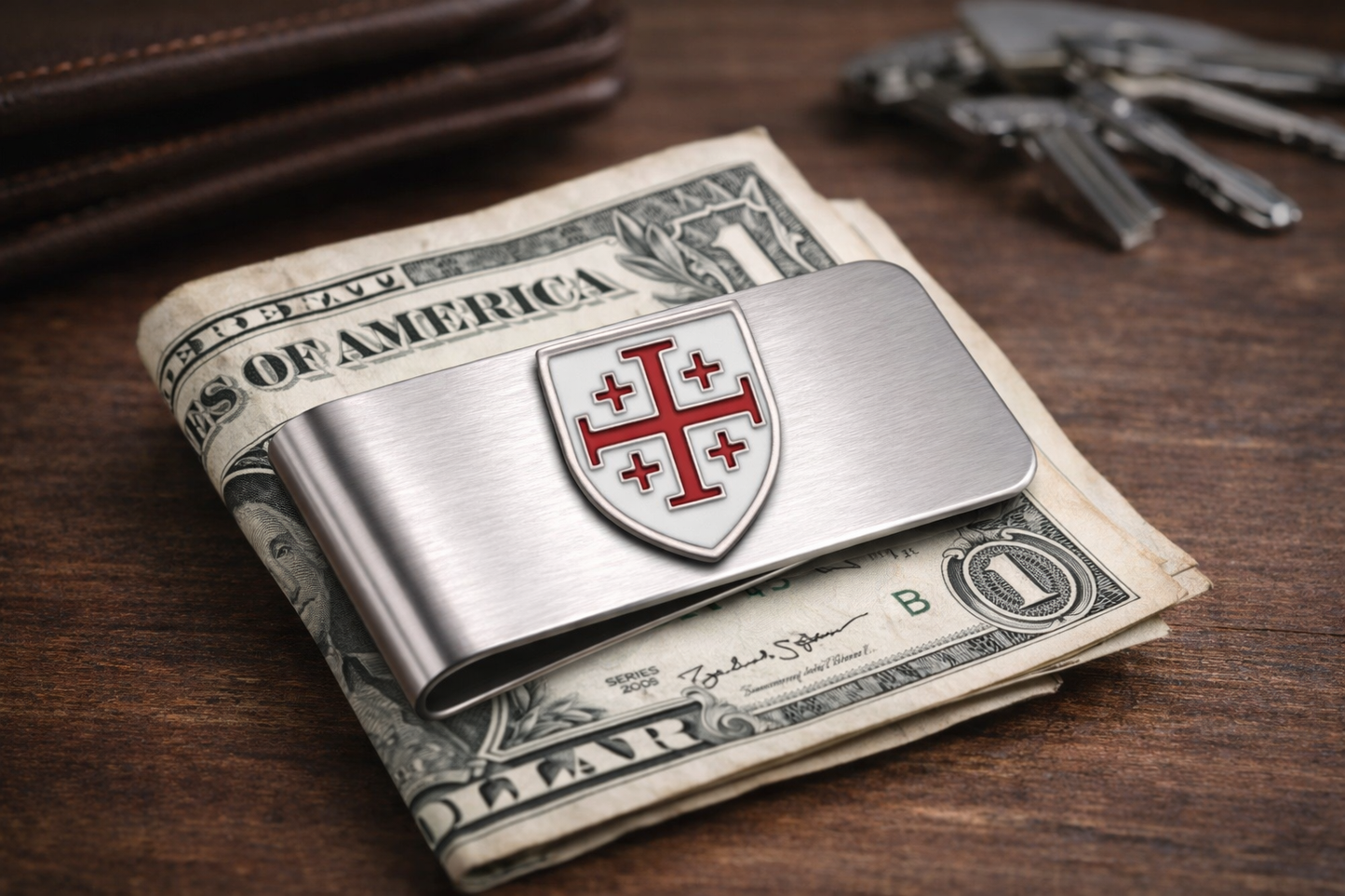 Silver money clip with a shield design on top of U.S. dollar bills on a wooden surface. Jerusalem Cross stainless steel money clip Christian men’s accessory