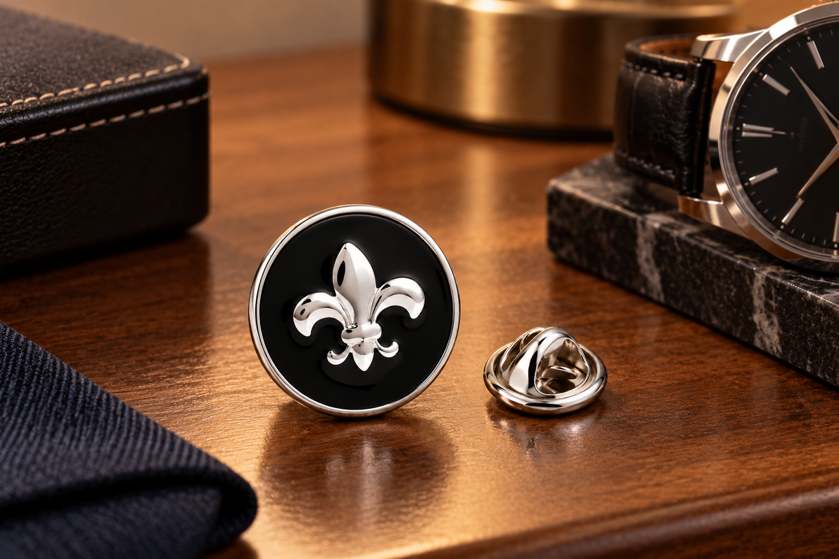 Black and silver Fleur de Lis lapel pin displayed with men's accessories