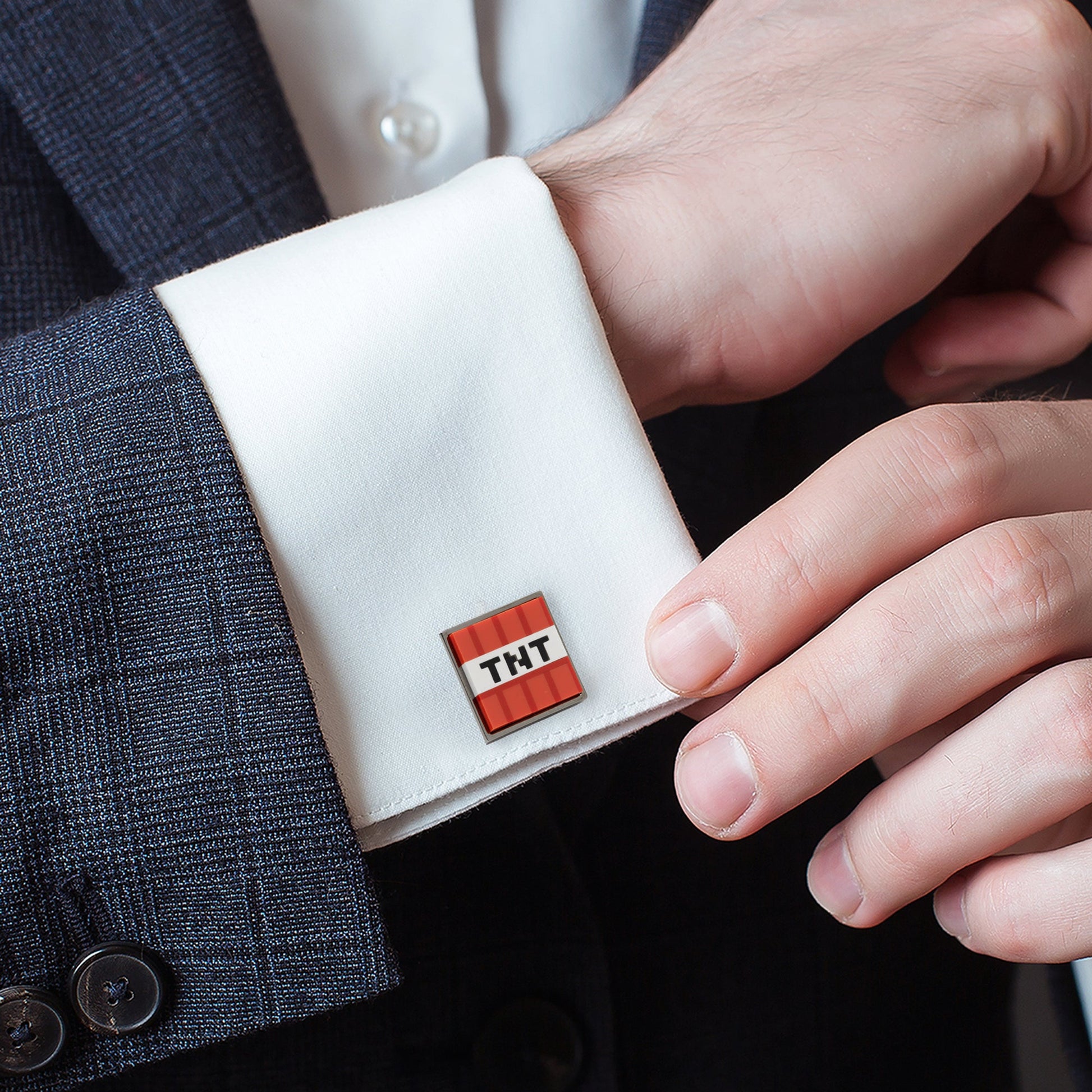 Cufflink with 'TNT' design on a white shirt cuff