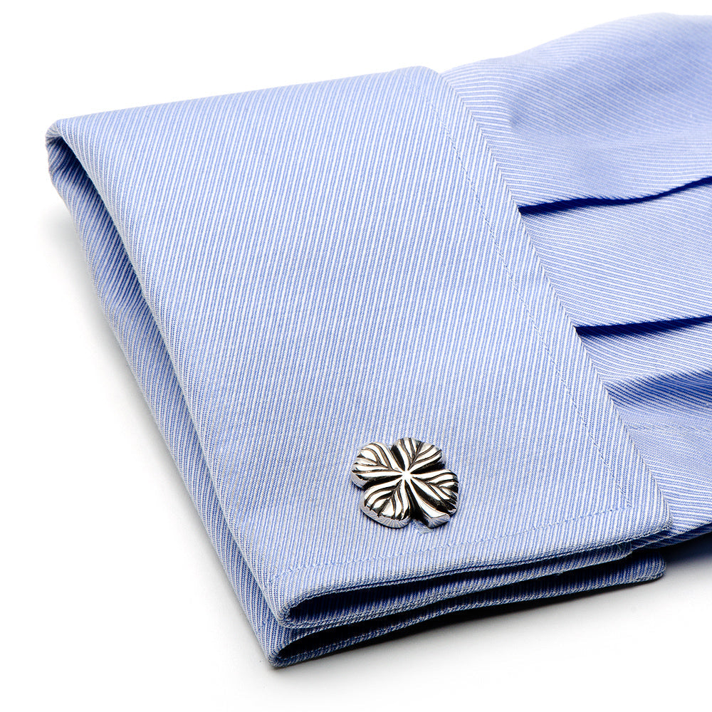 Silver cufflink on a folded blue shirt with white stripes