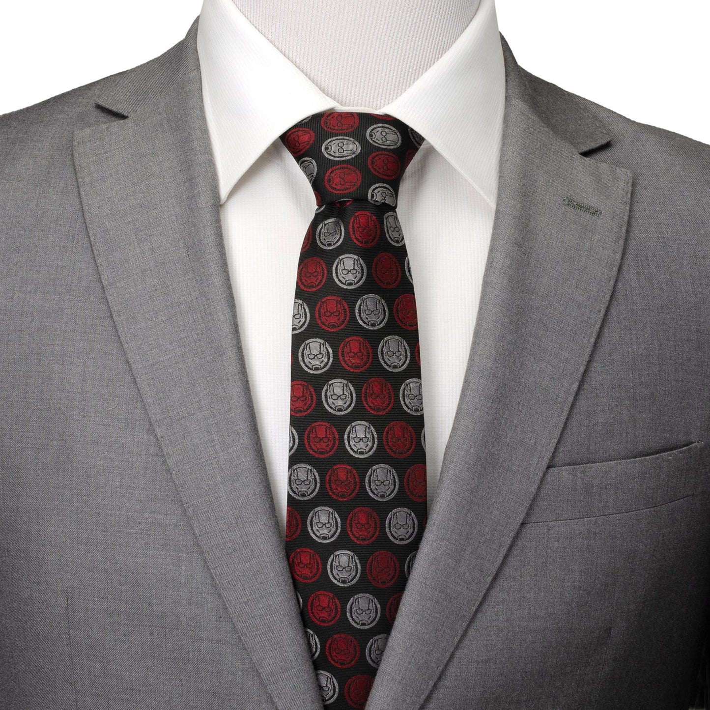 Gray suit jacket with a white shirt and red and black patterned tie on a mannequin.