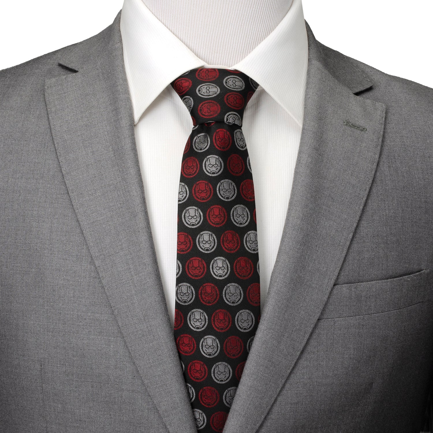 Gray suit jacket with a white shirt and red and black patterned tie on a mannequin.