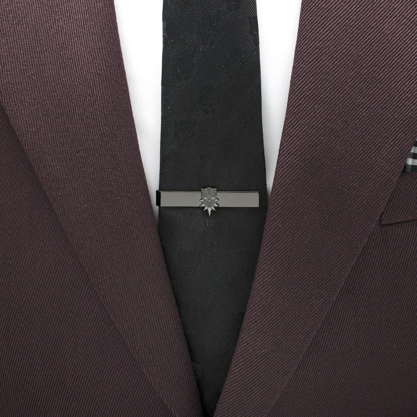 Close-up of a maroon suit with a black tie and silver tie clip on a white background