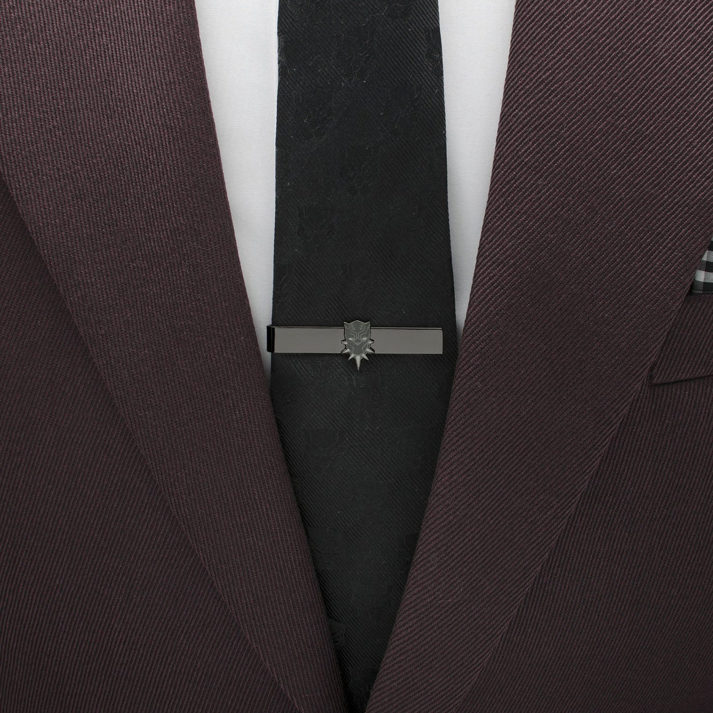 Close-up of a dark suit with a black tie and silver tie clip on a white background