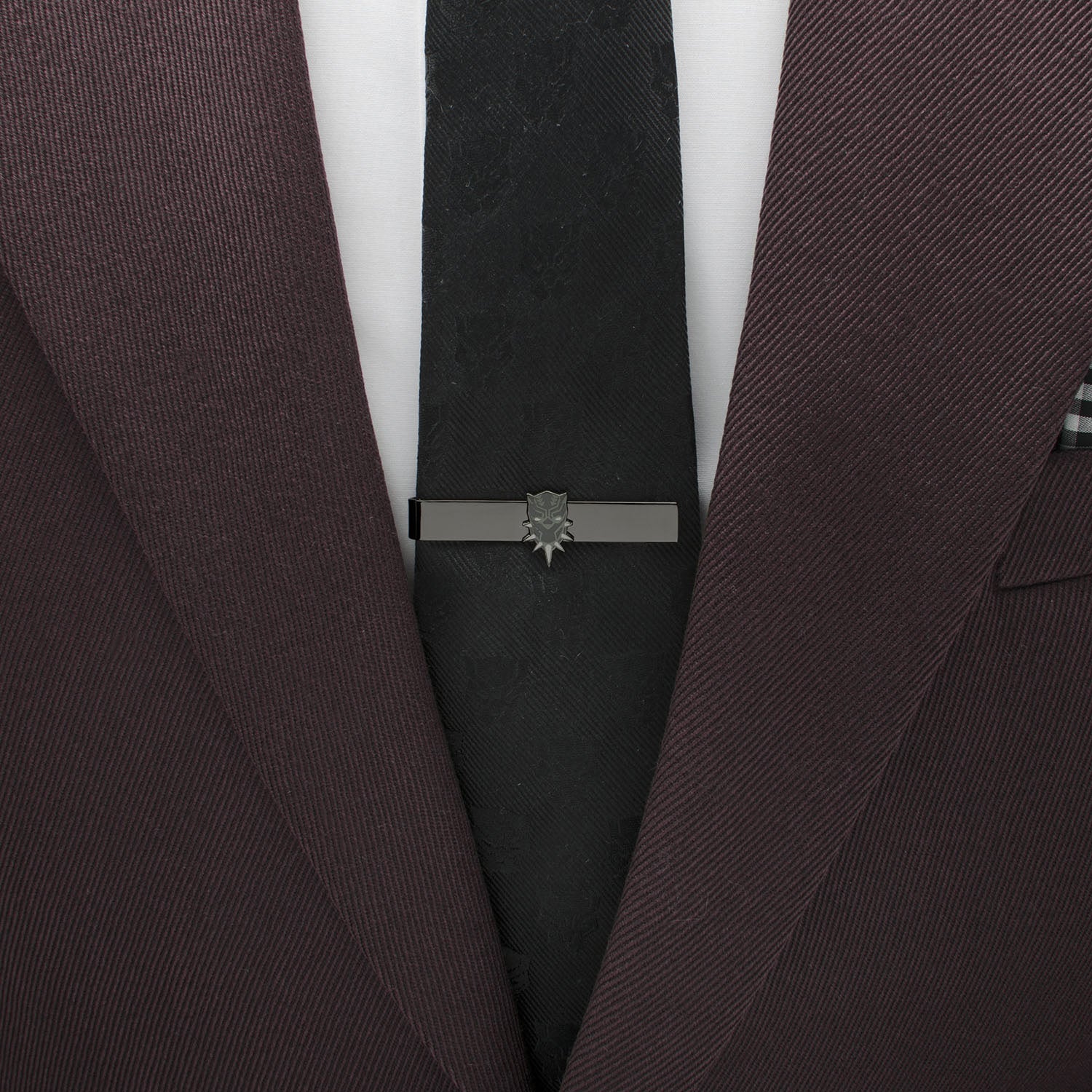 Close-up of a dark suit with a black tie and silver tie clip on a white background