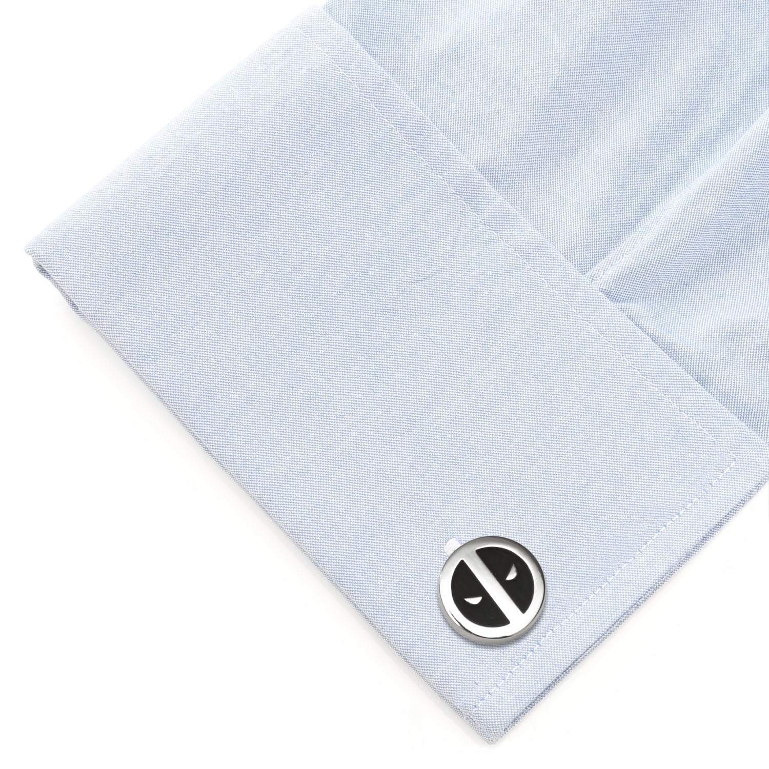 Cufflink on a light blue dress shirt with a white background