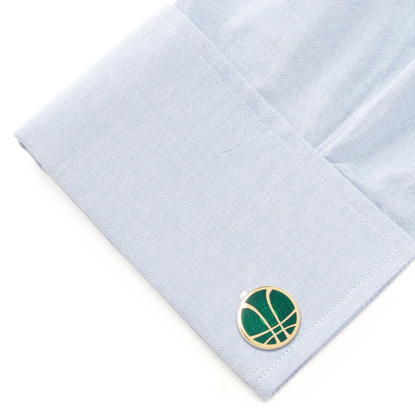 Cufflink with a green and gold design on a light blue shirt