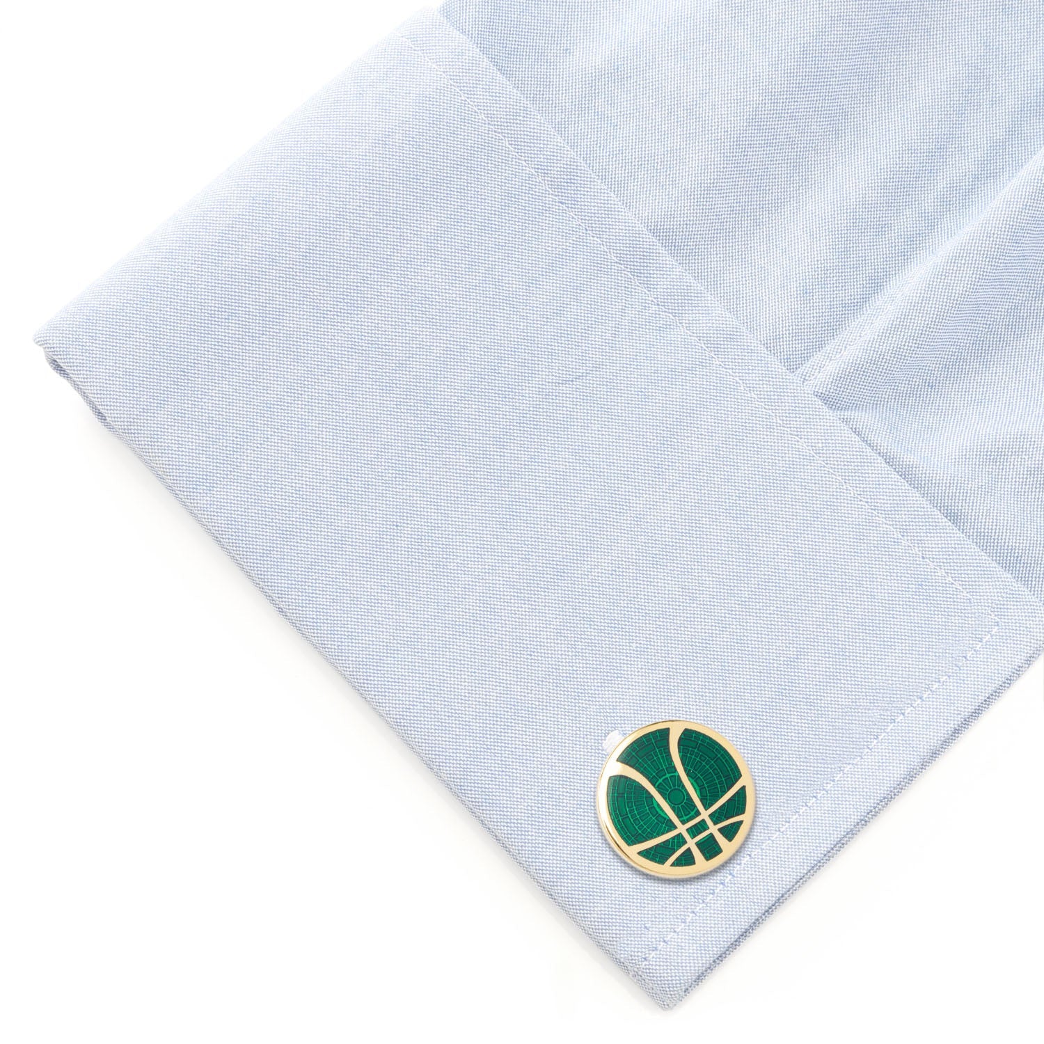 Cufflink with a green and gold design on a light blue shirt