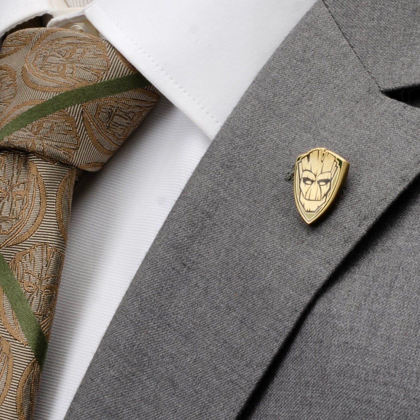 Gold emblem pin on a gray suit jacket with a patterned tie.