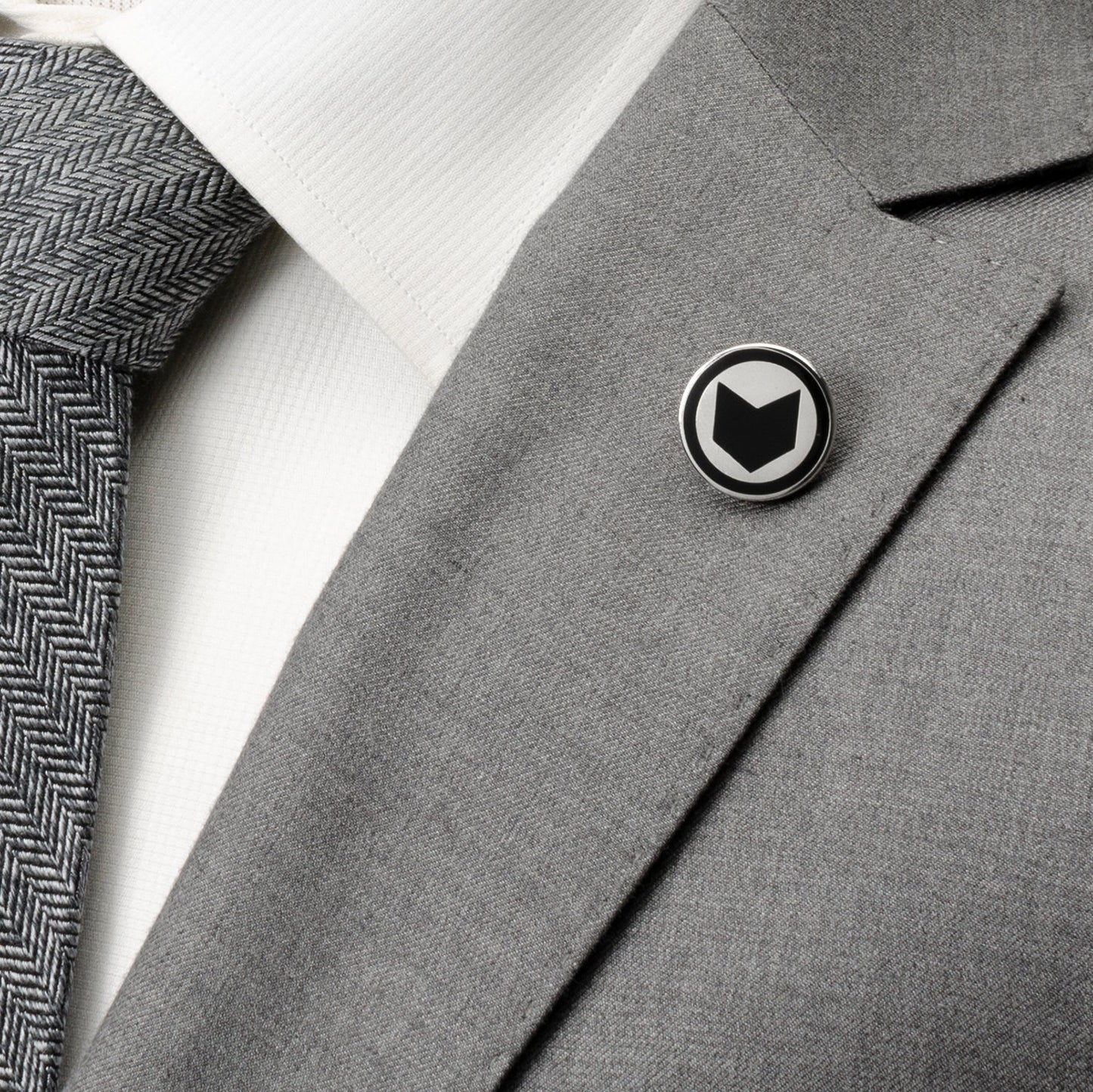 Gray suit jacket with a black and white logo pin on a white background Marvel Hawkeye Lapel Pin