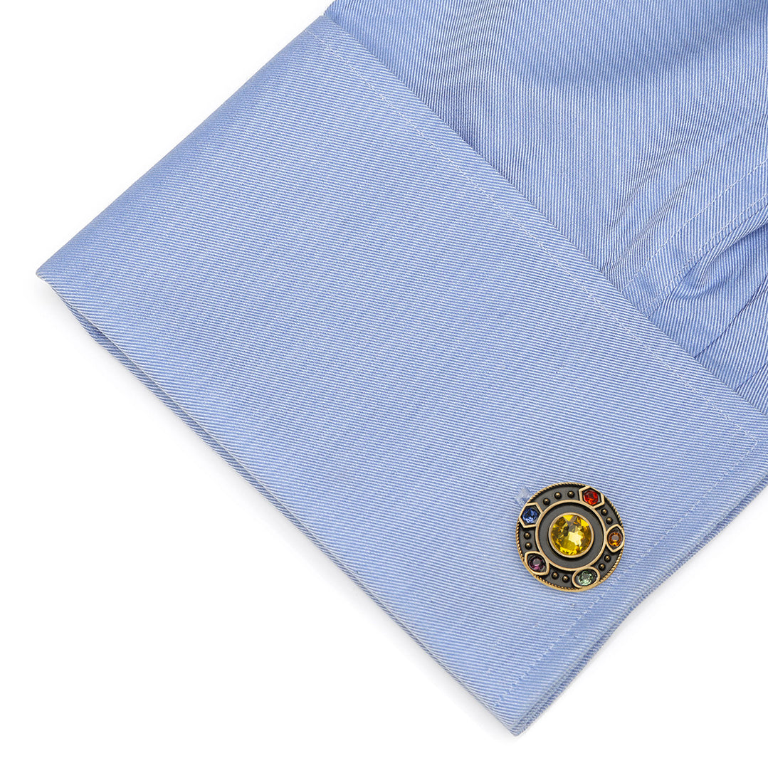 Close-up of a light blue shirt cuff with a decorative cufflink featuring a yellow gemstone.
