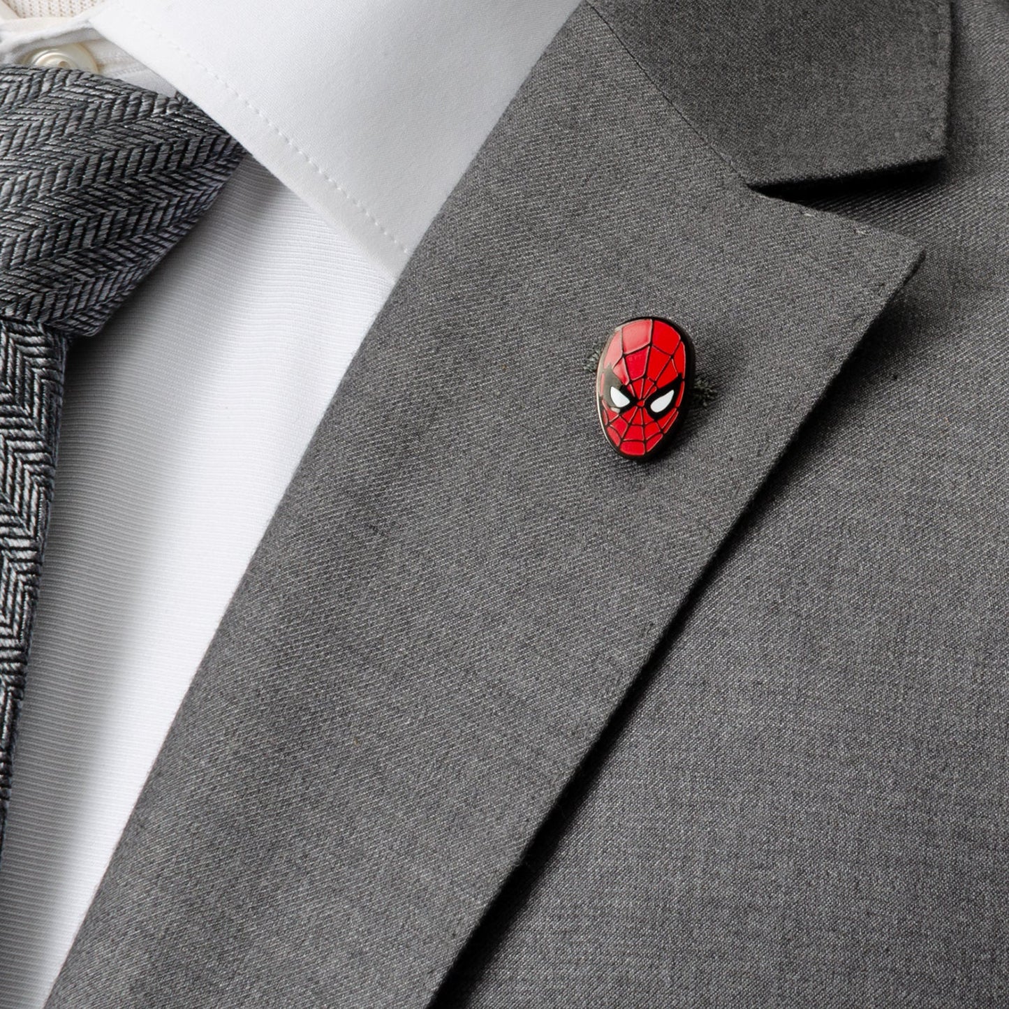 Spider-Man pin on a gray suit jacket with a white shirt and gray tie.
