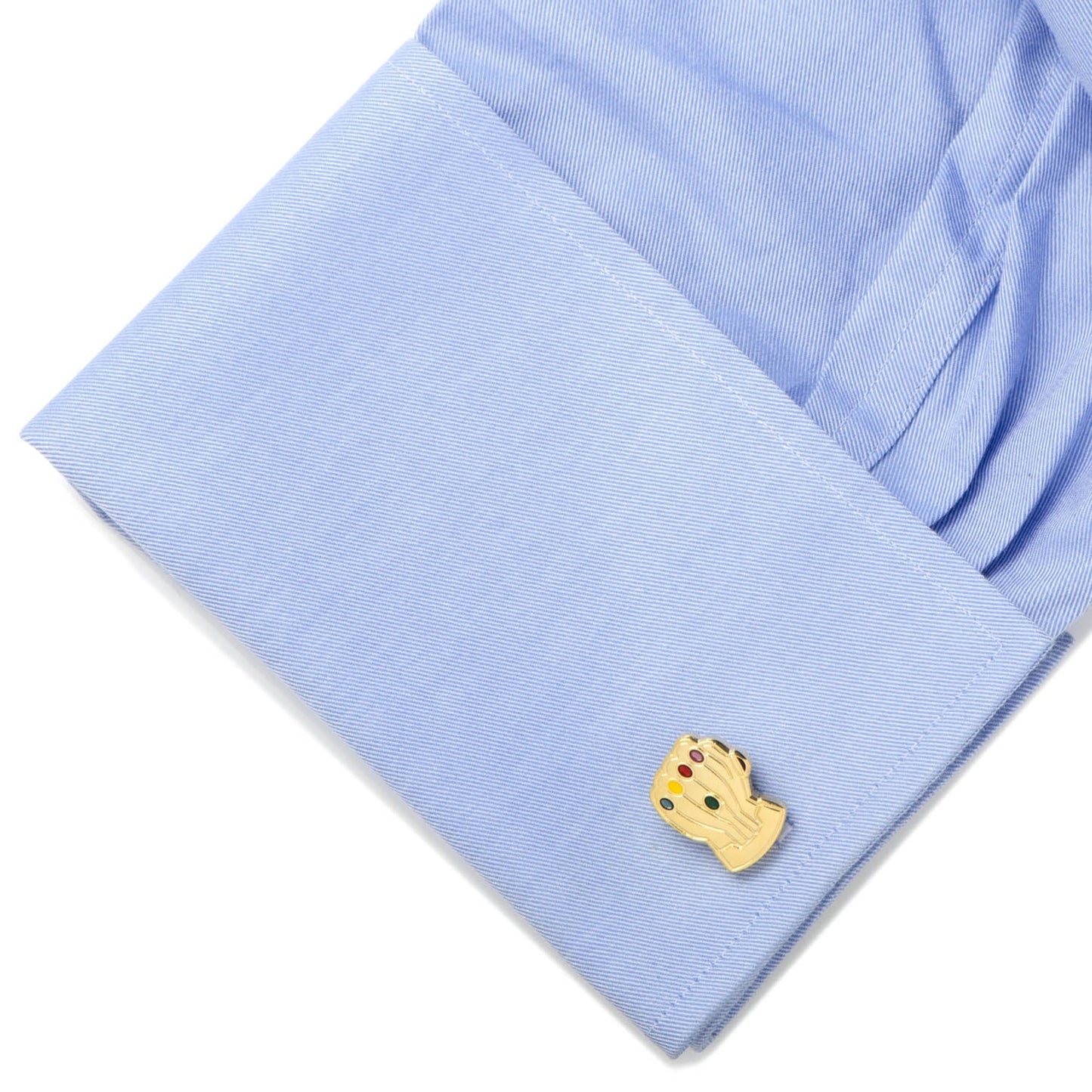 Gold cufflink on a light blue fabric background