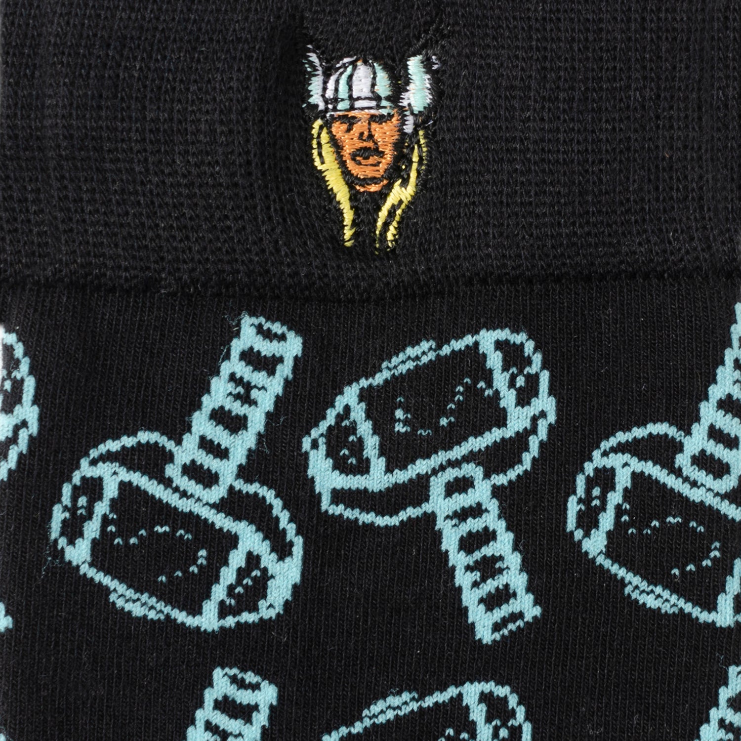 Black beanie with embroidered face design and patterned hammer design on a black background
