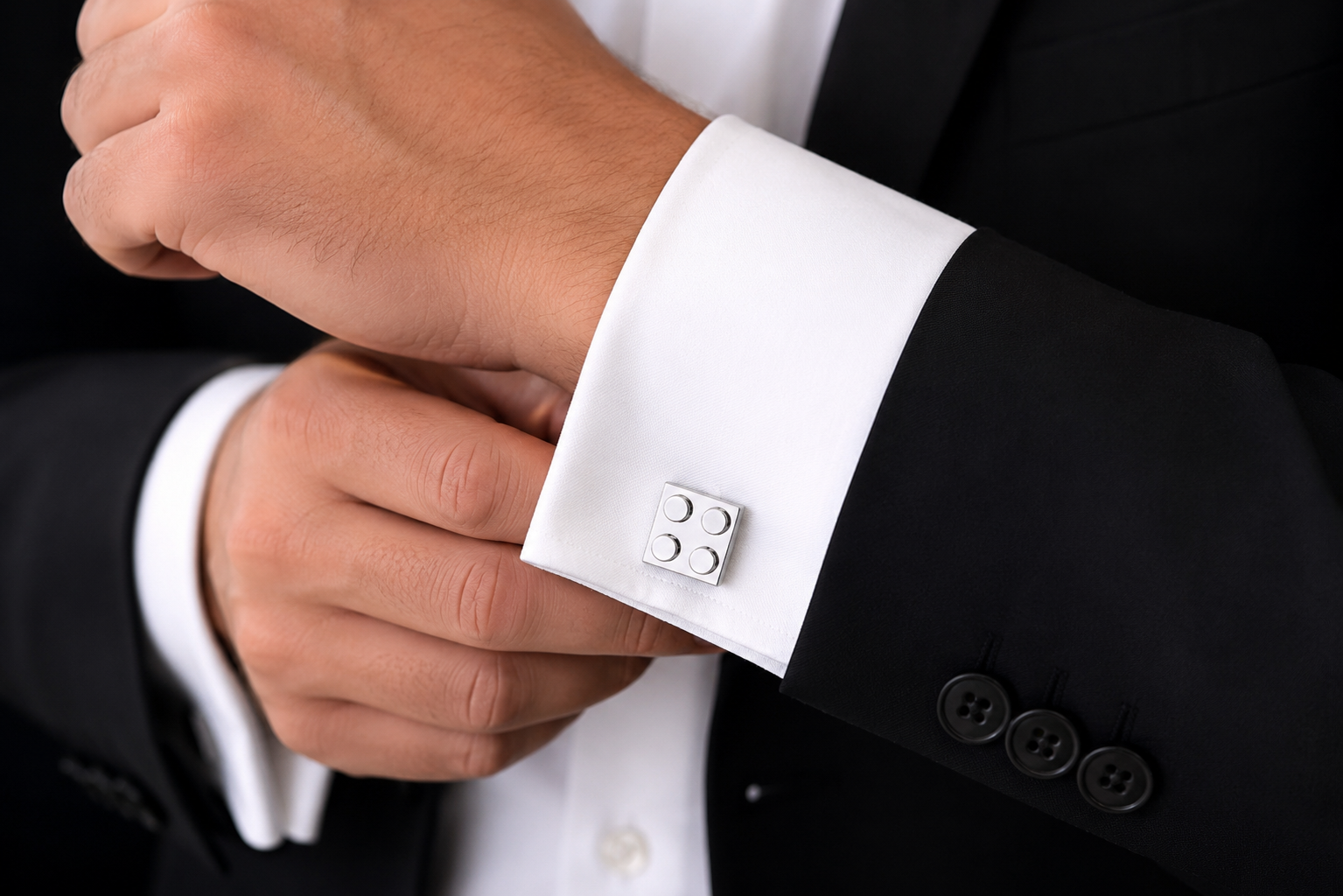 Close-up of a person adjusting a cufflink on a black suit with white shirt