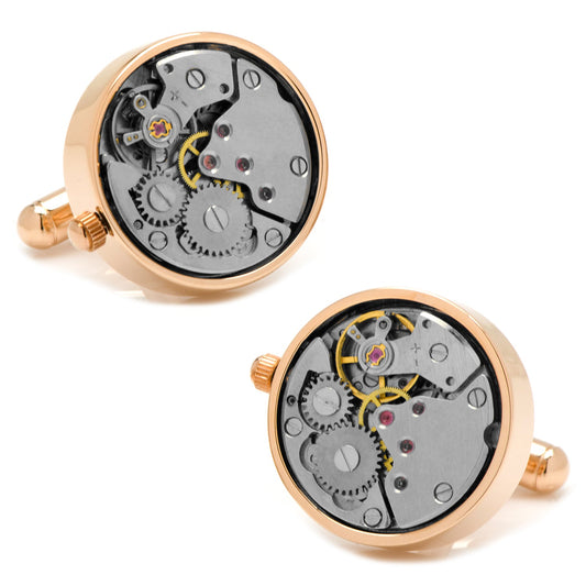 Two gold cufflinks with mechanical watch movements on a white background