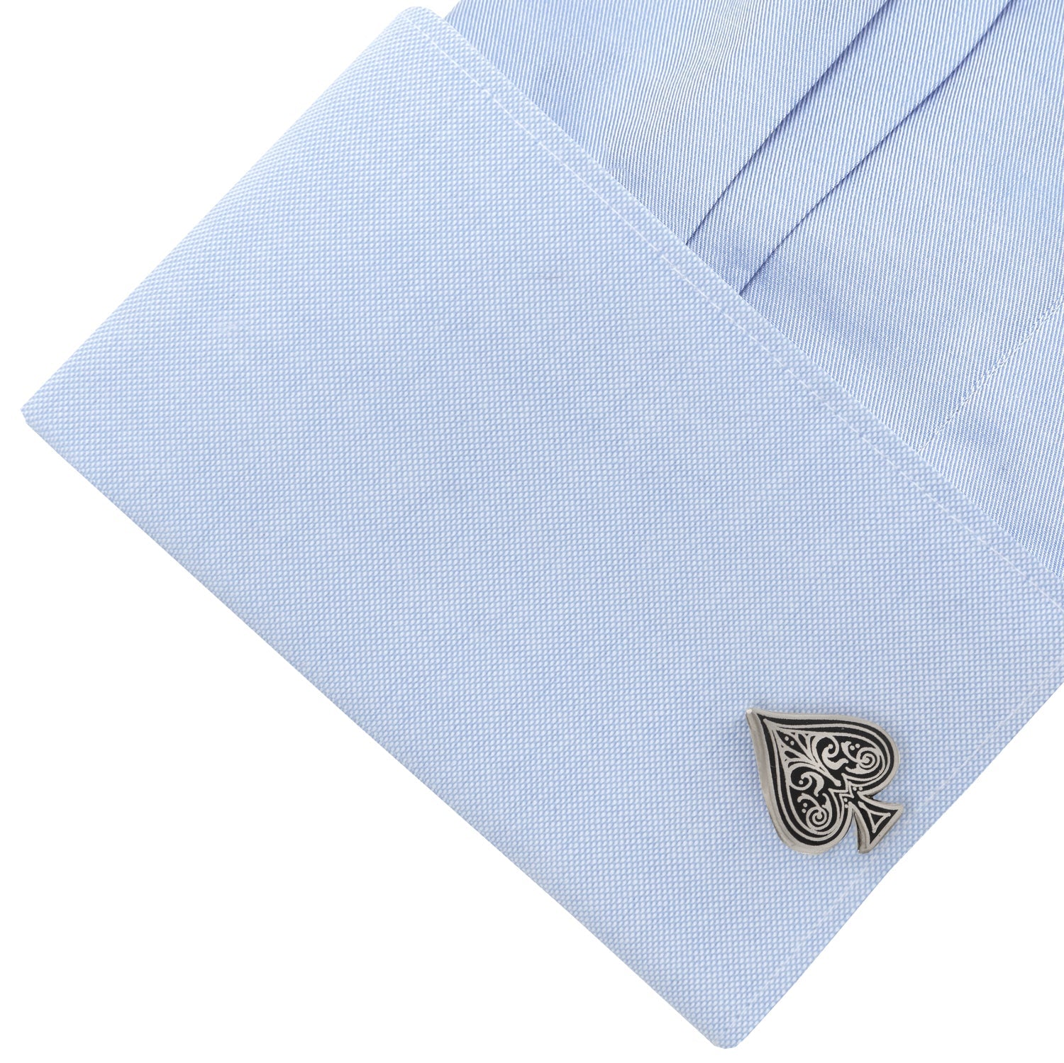 Cufflink on a light blue dress shirt with a white background