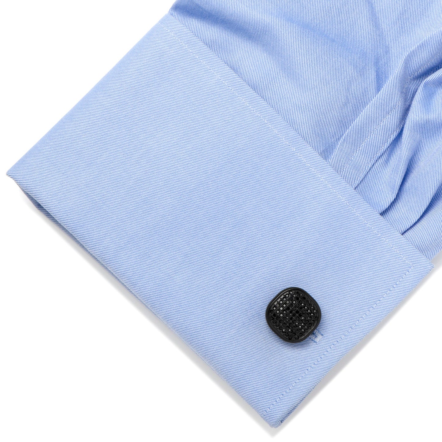 Close-up of a light blue shirt cuff with a black button on a white background