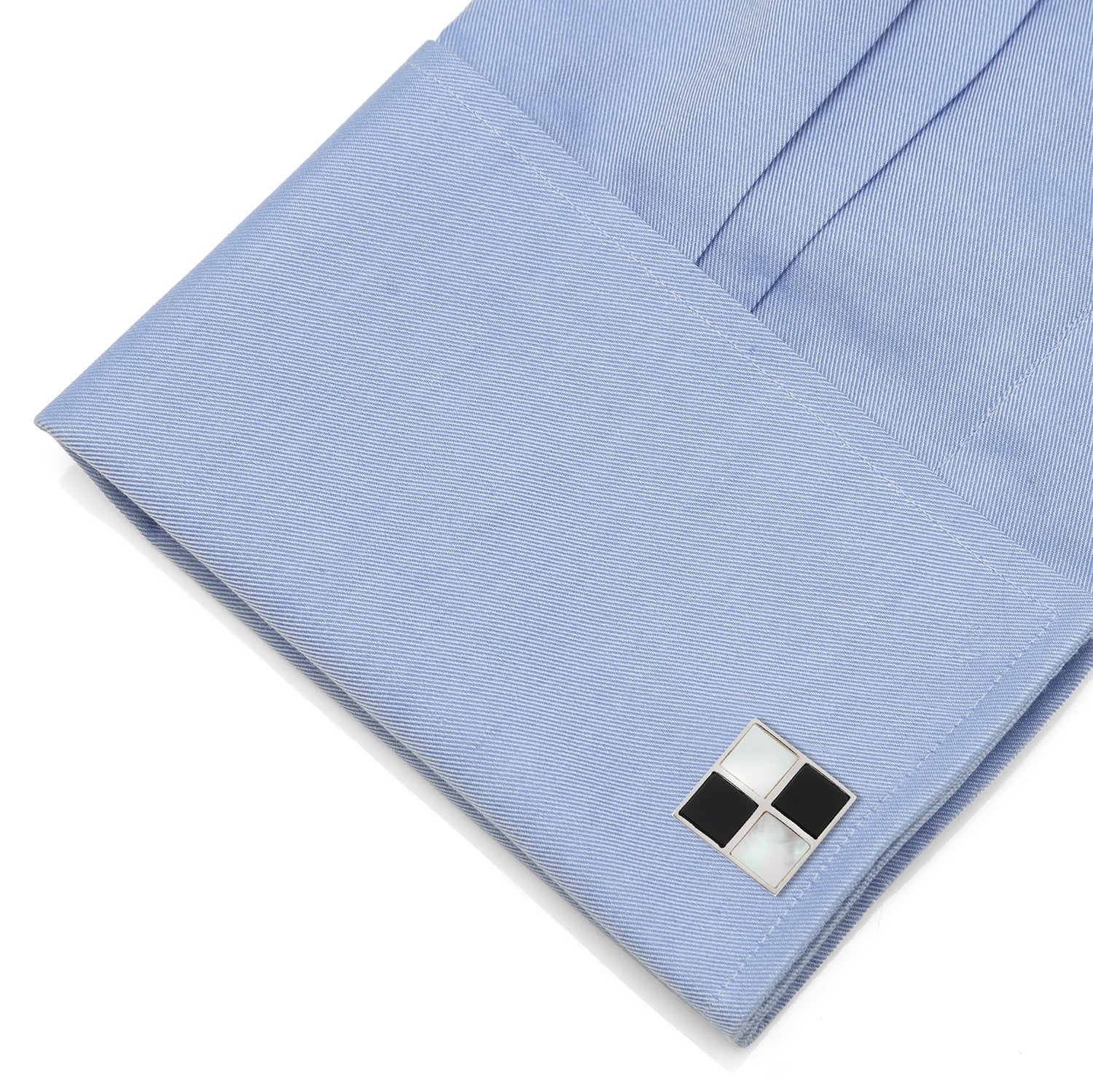 Close-up of a blue pocket square with a silver and black cufflink on a white background