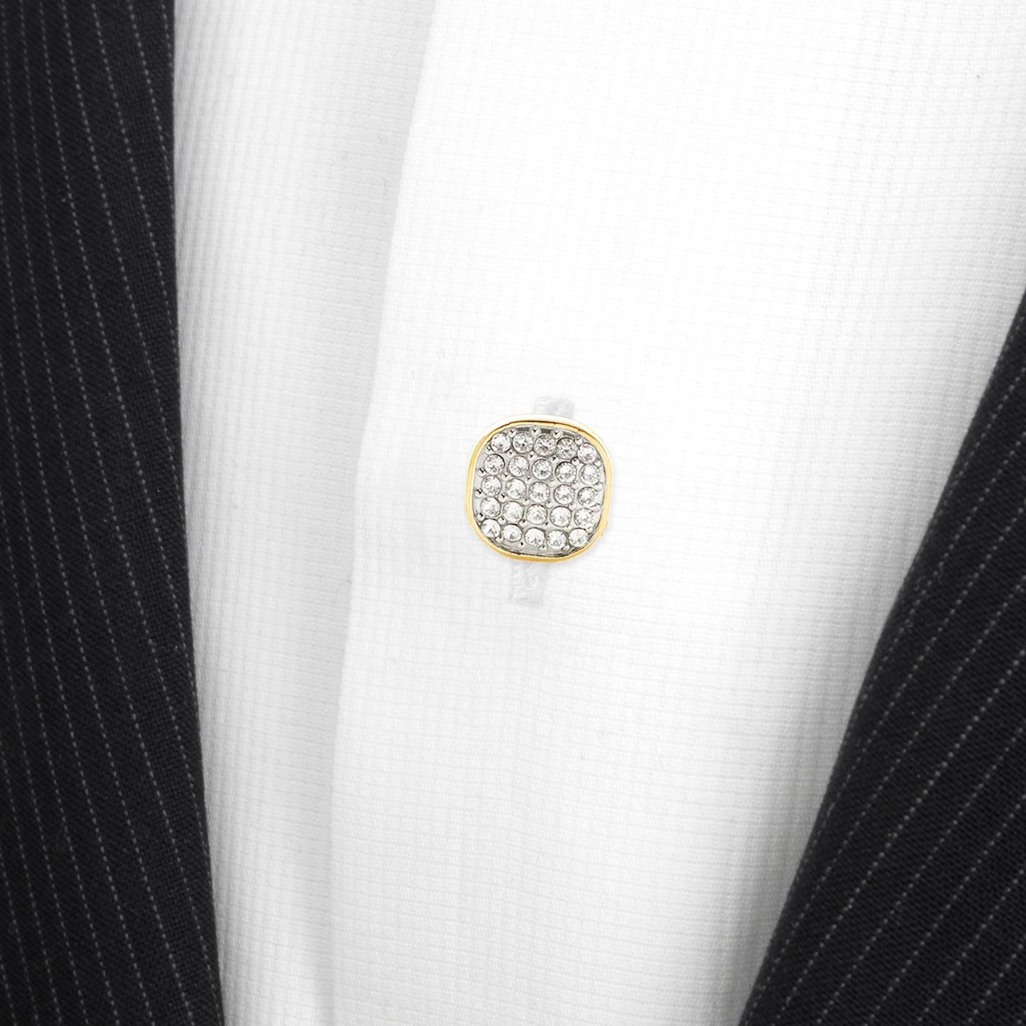 Gold cufflink with gemstones on a white shirt with black pinstripes