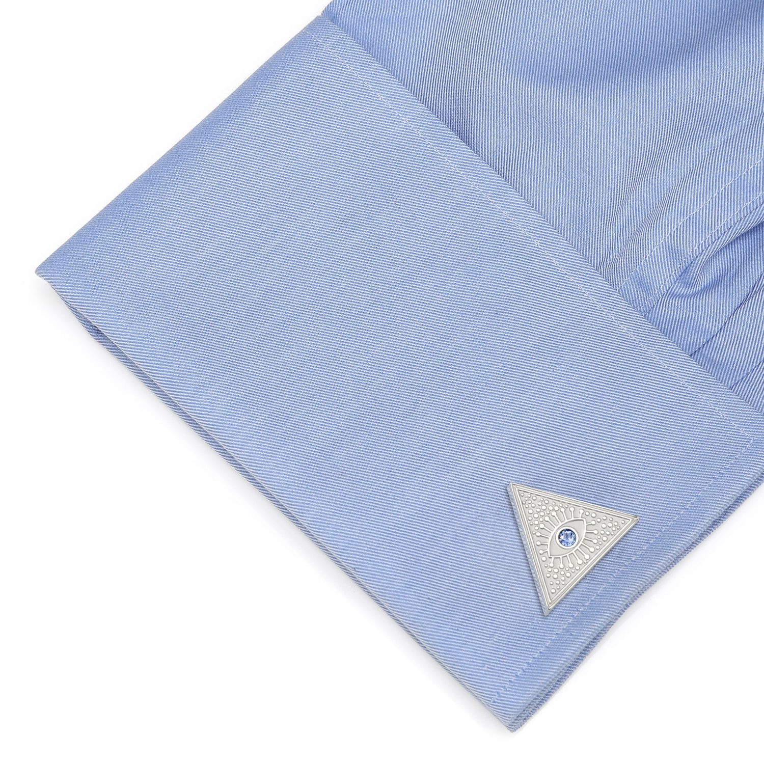 Close-up of a light blue shirt with a silver cufflink on a white background