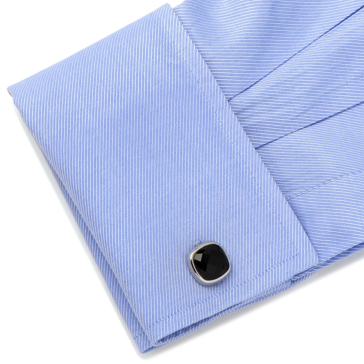 Folded blue striped shirt with a black button on a white background
