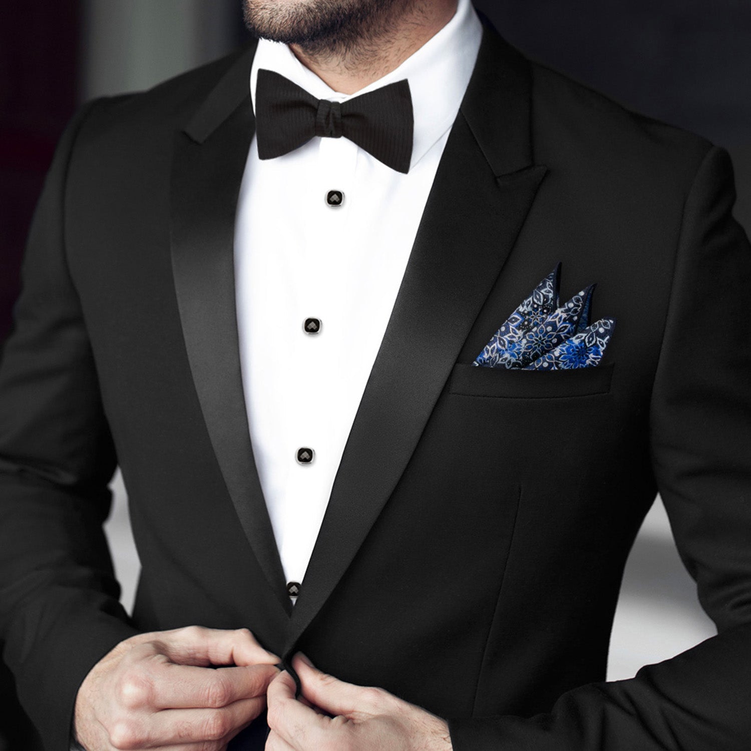 Man wearing a black tuxedo with a white shirt and blue pocket square.