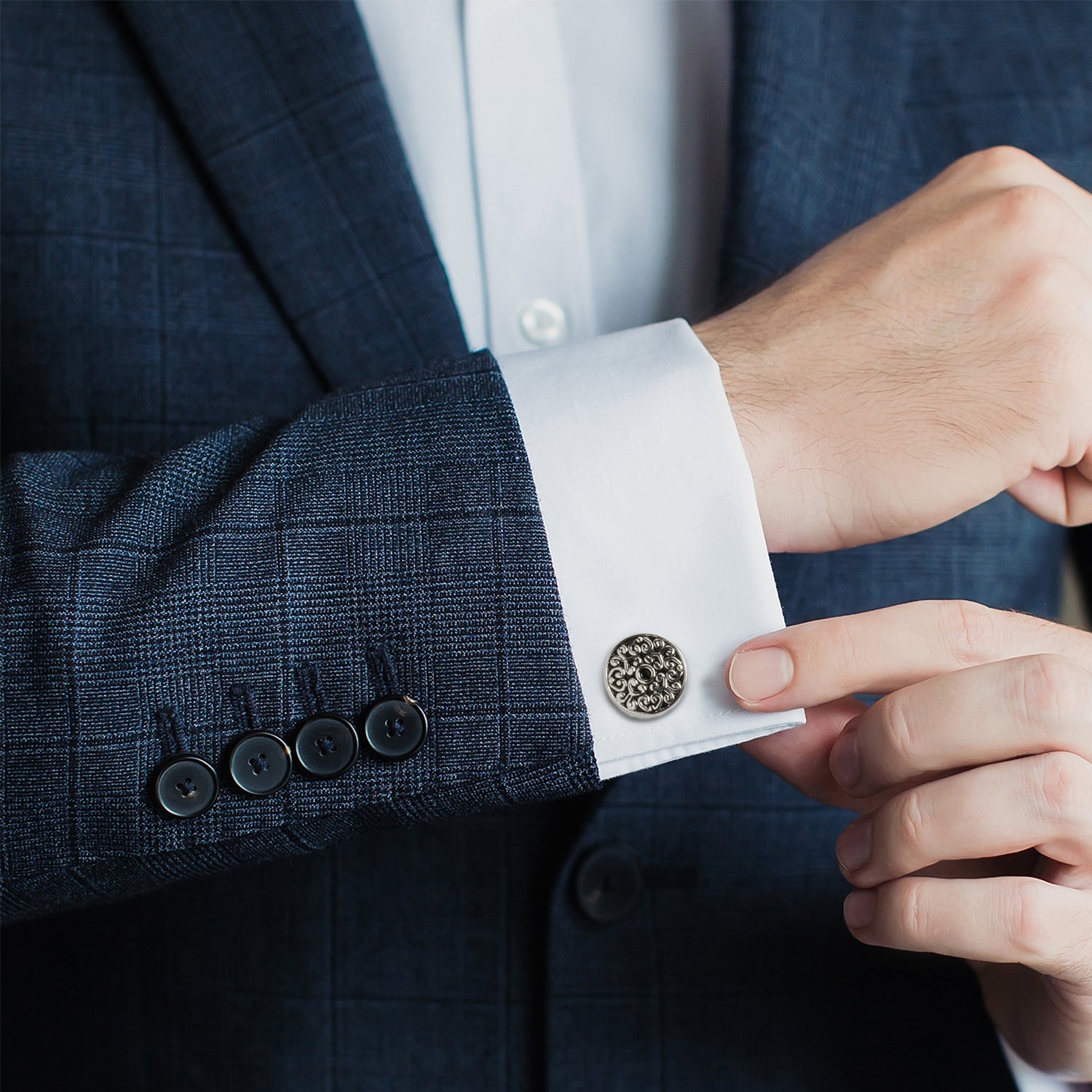 Close-up of a person adjusting a cufflink on a suit sleeve.