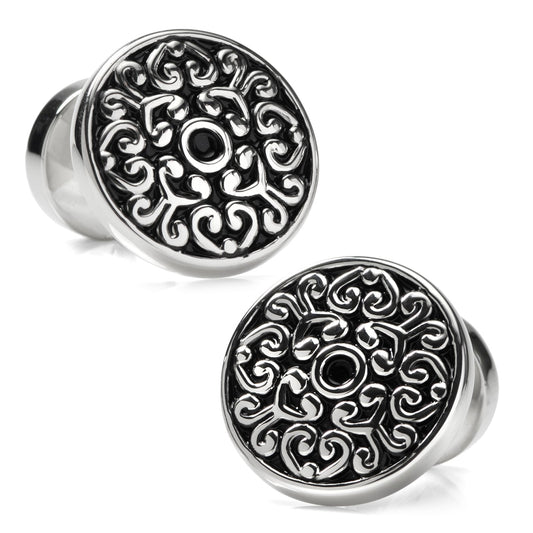 Pair of silver cufflinks with intricate black designs on a white background