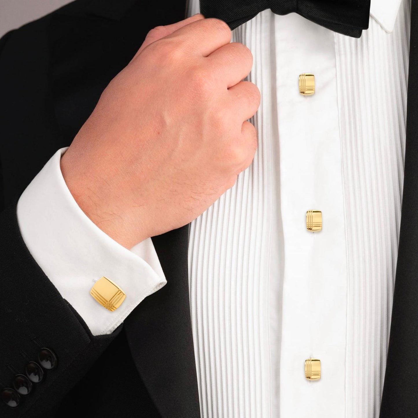 Close-up of a tuxedo with gold buttons and white shirt cuff.