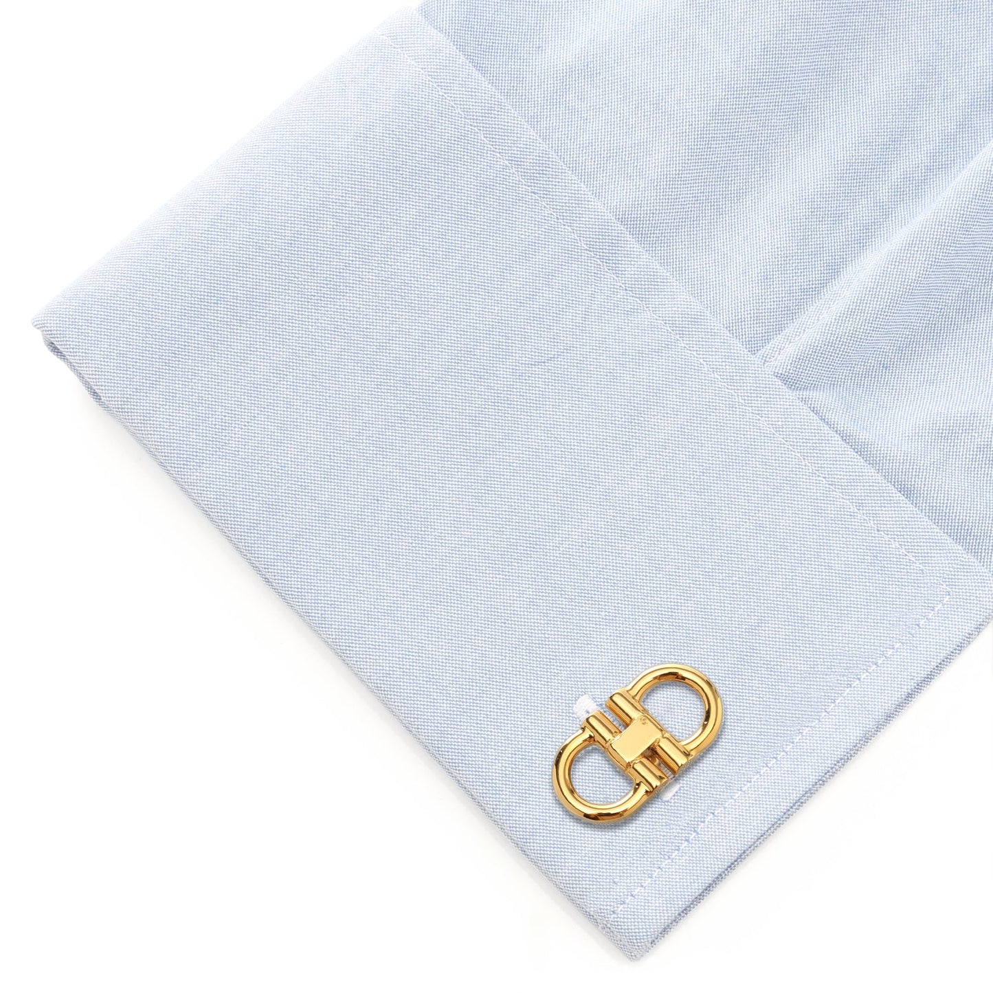 Gold cufflink on a light blue dress shirt