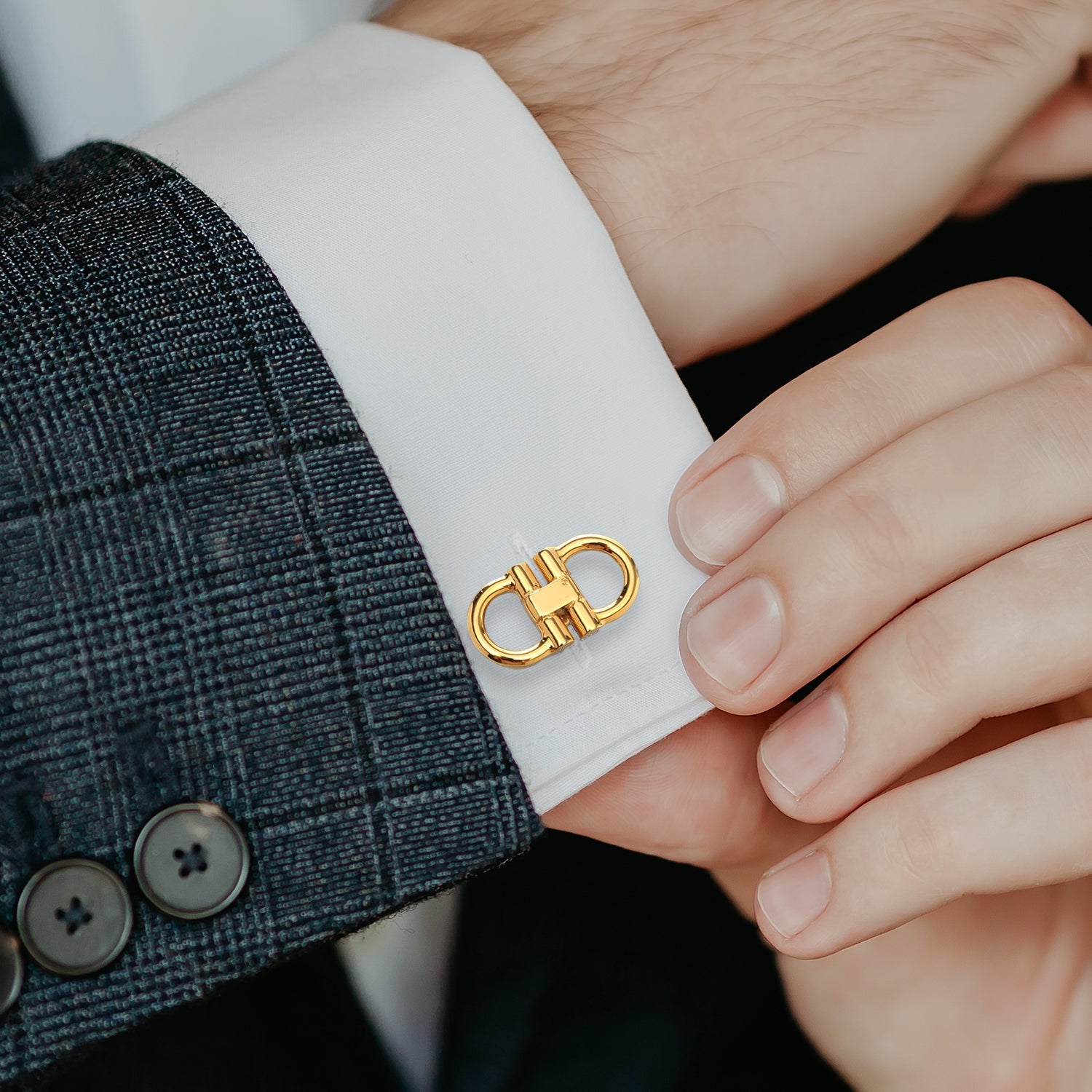 Gold cufflink on a white shirt cuff with a suit jacket
