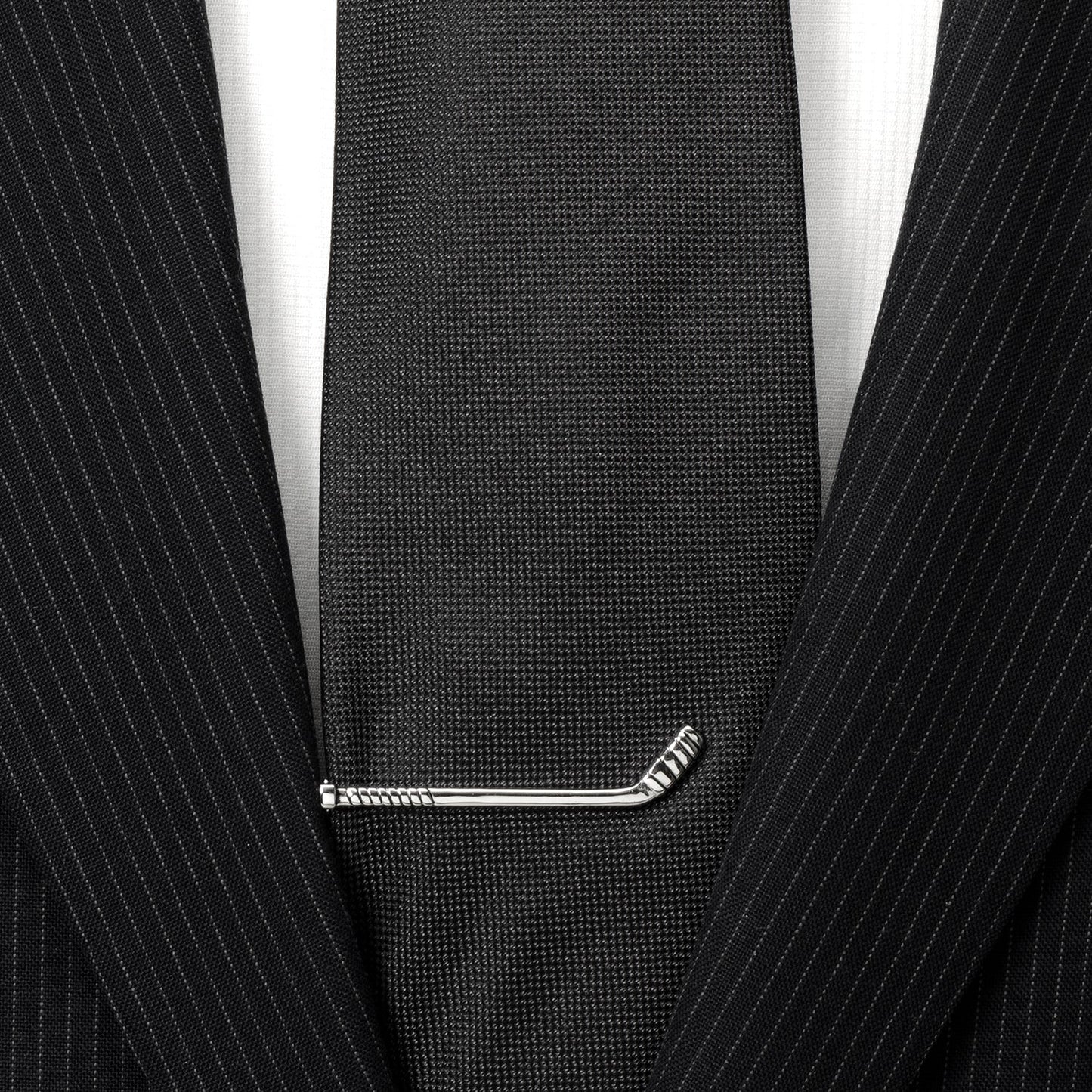Black tie with a silver tie clip on a black pinstripe suit jacket.