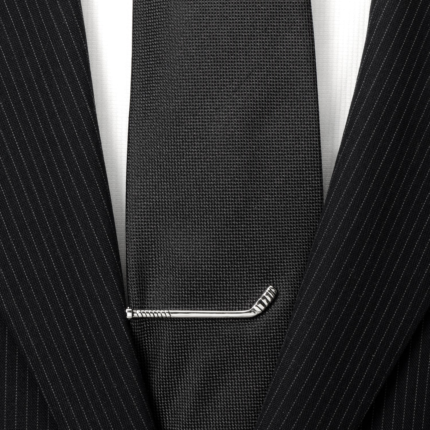 Black tie with a silver tie clip on a black pinstripe suit jacket.