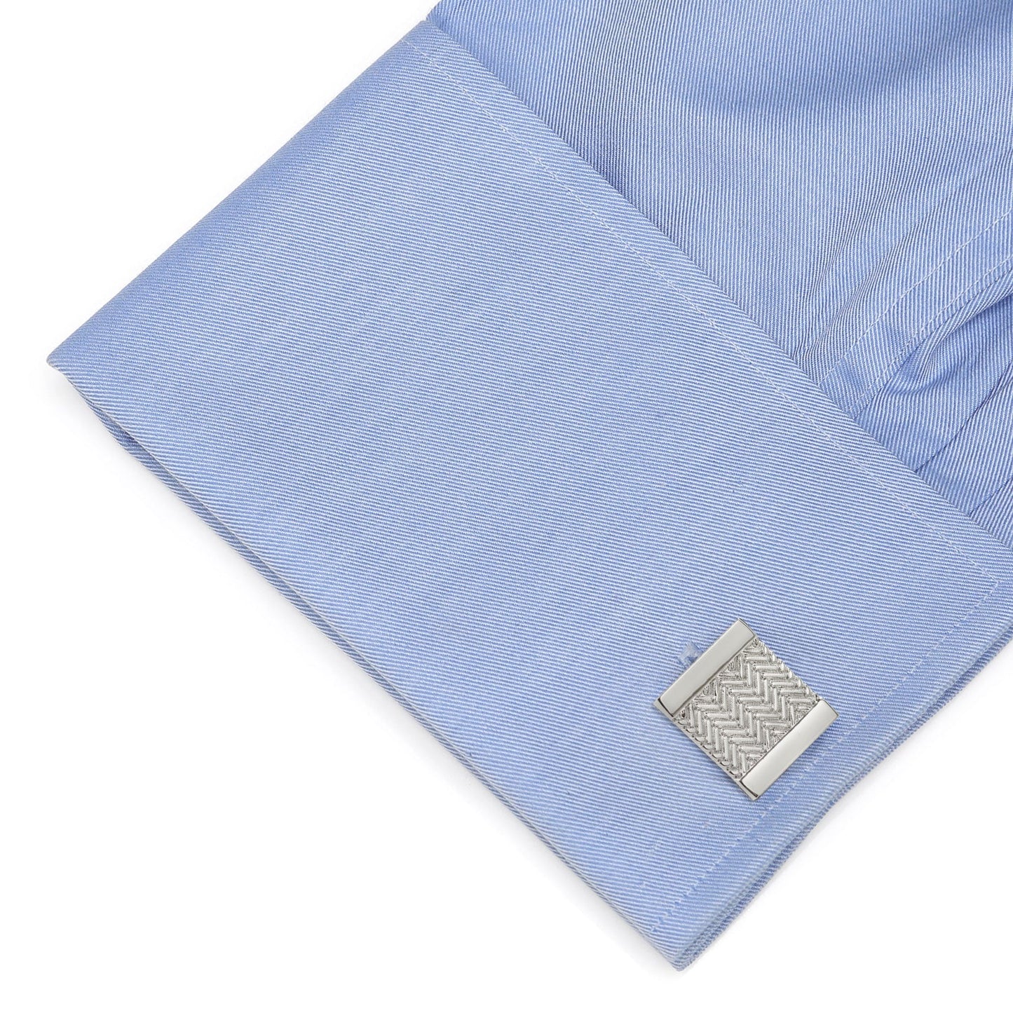 Close-up of a light blue shirt cuff with a silver cufflink on a white background