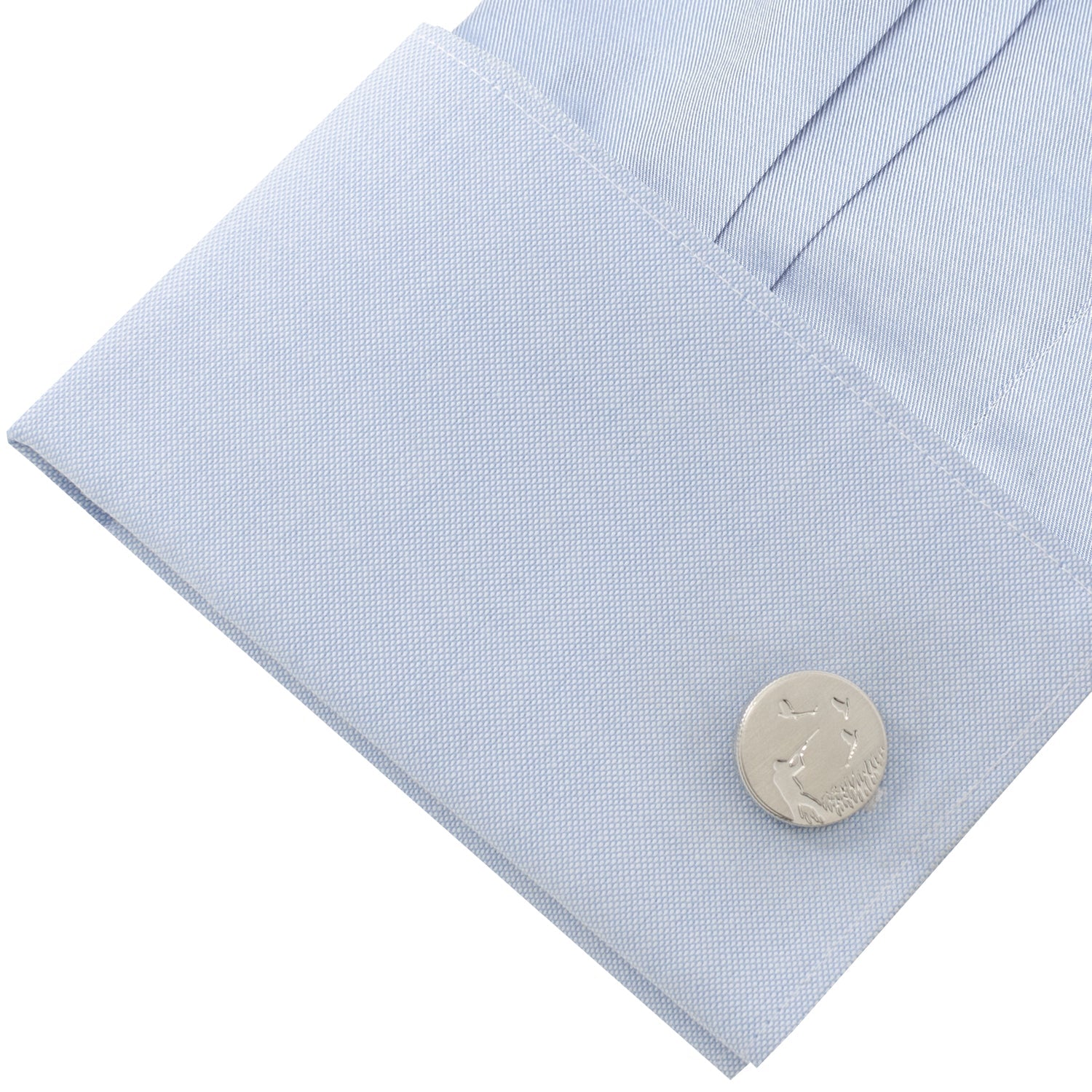 Close-up of a light blue shirt with a silver cufflink on a white background