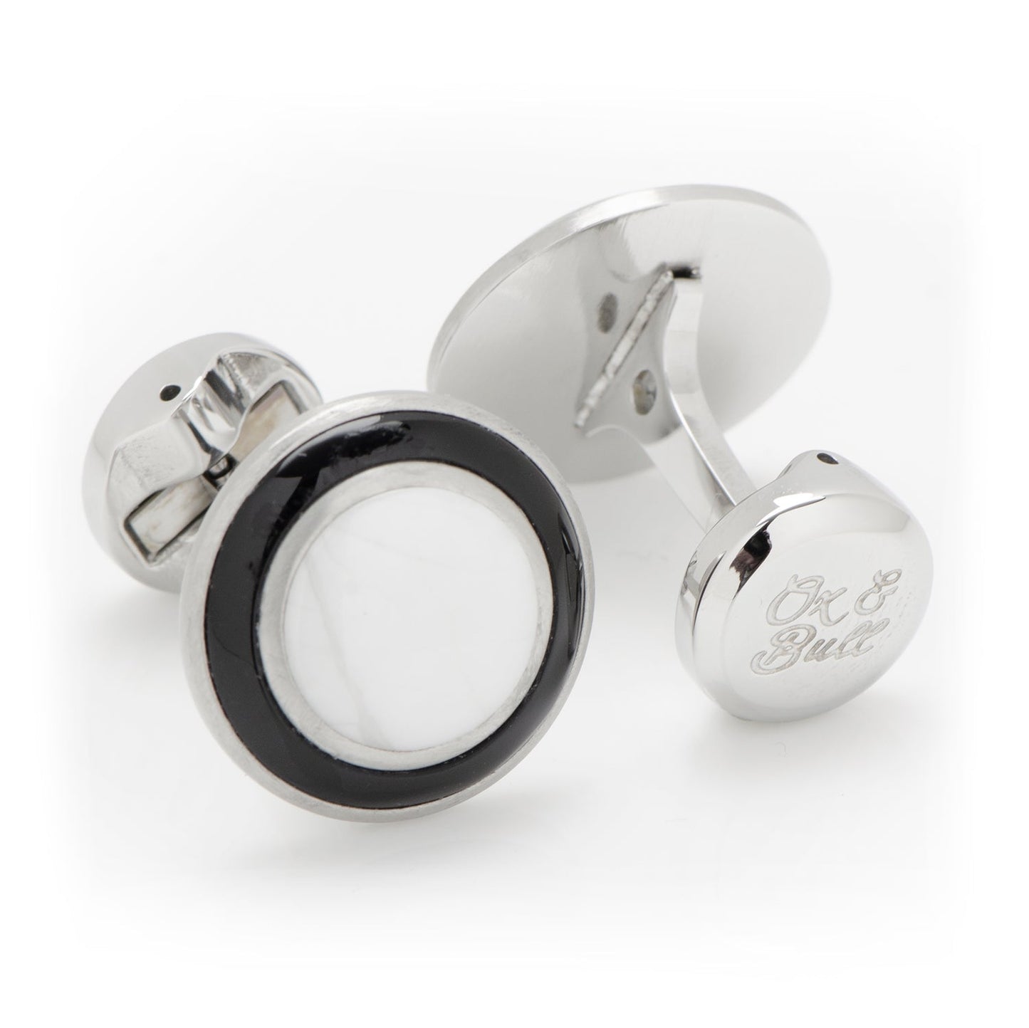 Silver cufflinks with a black and white circular design on a white background