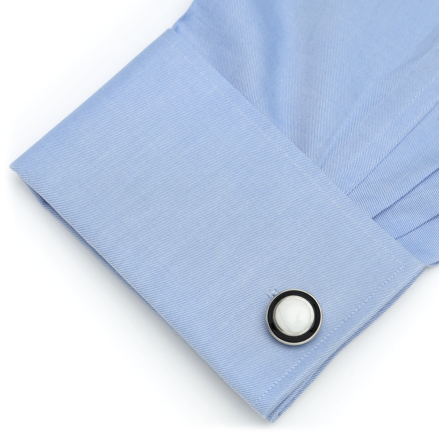 Close-up of a light blue shirt cuff with a button on a white background